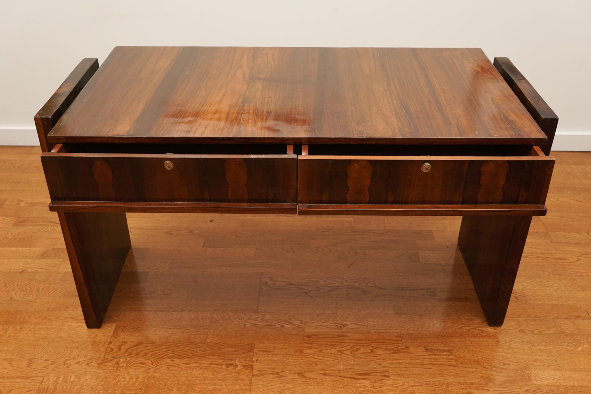 Joaquim Tenreiro (1906–1992) was among the leading furniture designers and visual artists in mid-20th century Brazil.  The Tenreiro-designed desk, shown here, is made in solid wood and Brazilian rosewood veneer.  The desk top is floated between