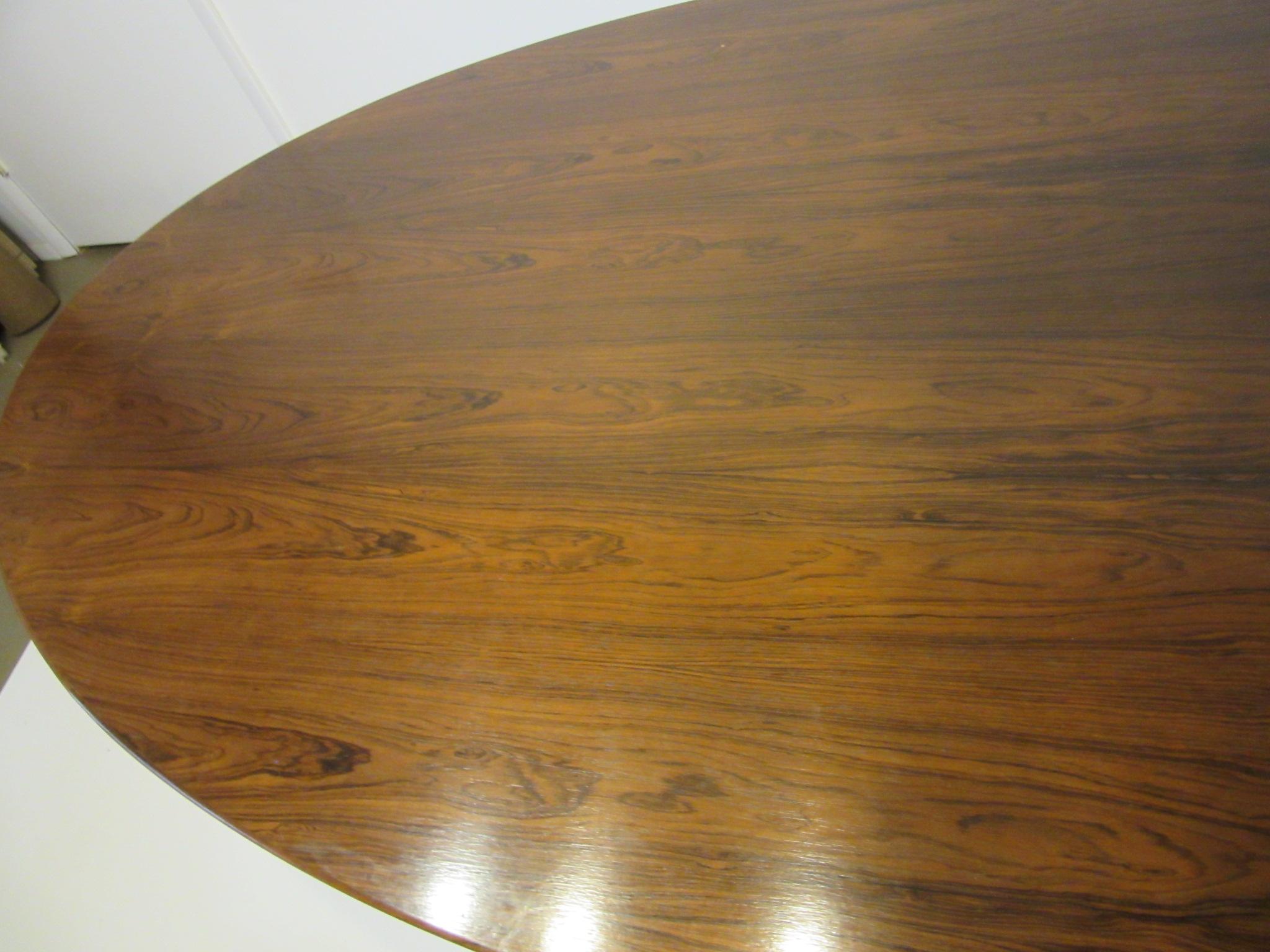 A dark richly grained large oval Brazilian rosewood dining table with beveled edge supported by a polished chrome heavy gauge steel four star base . Retains the original manufactures label Knoll Associates Inc. Madison Ave. NYC . The largest size