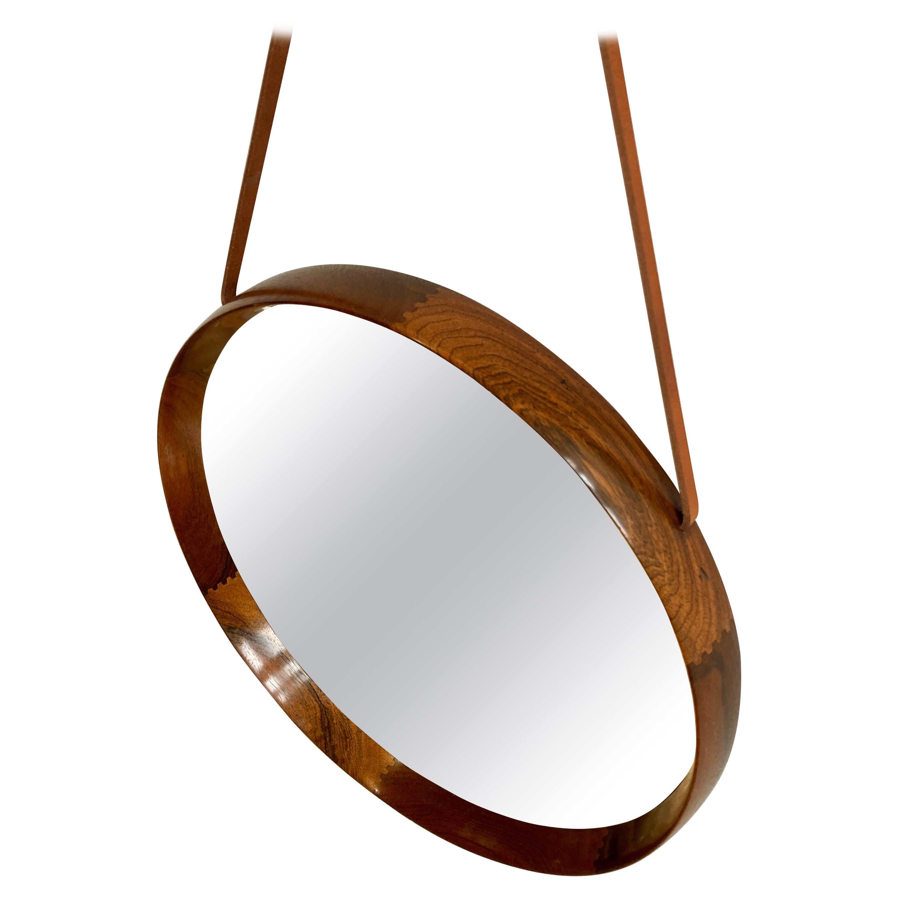 Extremely pretty and very hard to find wall mirror designed by Uno & Osten Kristiansson for Swedish firm Luxus.

Beautifully recessed solid Brazilian rosewood frame with pleasing visible joinery. The mirror hangs on an intergrated leather