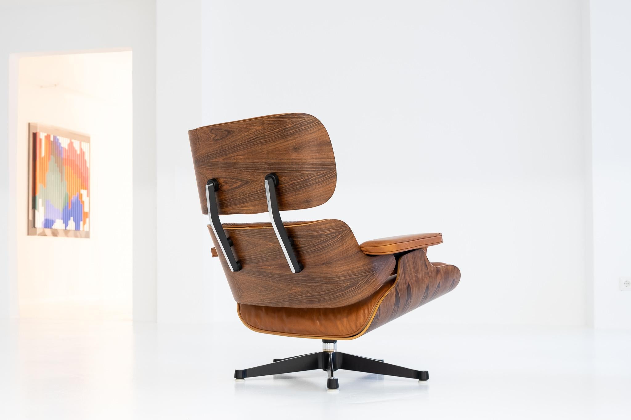 Eames Lounge Chair, Brazilian rosewood veneer (CITES available), covered with super soft cognac-colored leather. Fully restored and documented by our Vitra-certificated restorer. Restoration incl. veneer, cushions, shockmounts and rotating parts. We