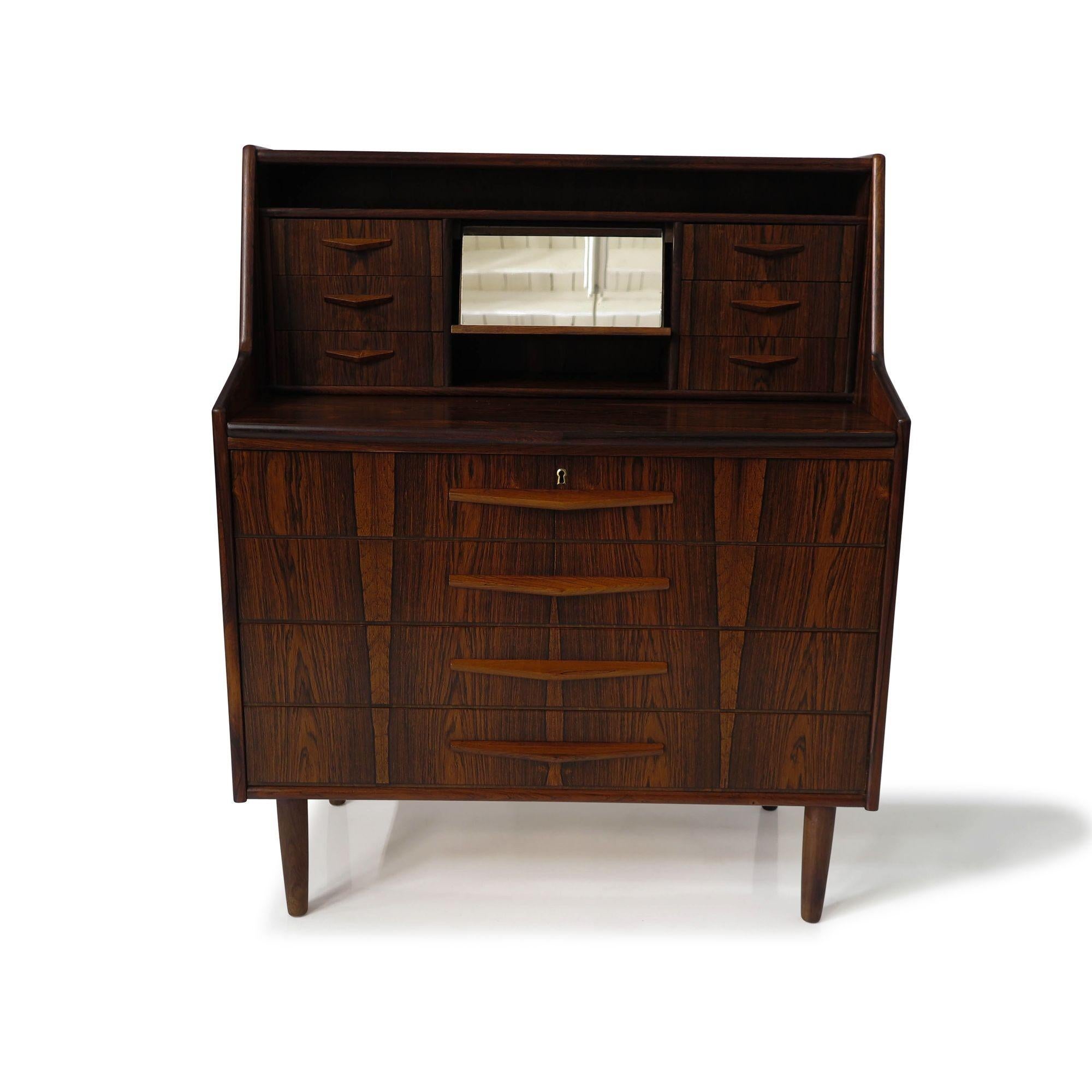 Brazilian rosewood secretary desk, 1955, Denmark. Crafted with exquisite attention to detail, it showcases stunning Brazilian rosewood with dark grains and dynamic book-matched patterns on the drawer fronts and sides. The secretary boasts six small