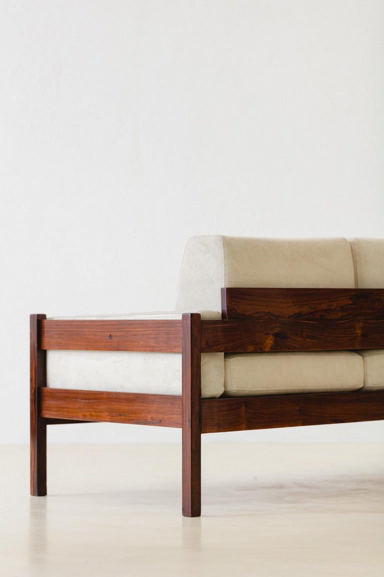 Brazilian company Celina Decorações manufactured this sofa in the 1960s. The piece is composed of a solid Rosewood structure, with cushions upholstered with leather. 

This three-seat sofa has detached cushions, a widespread threat at the time