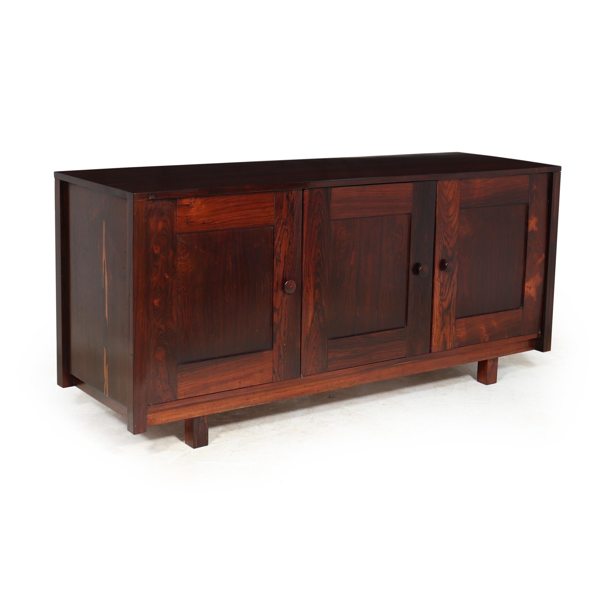 A mid century sideboard produced in Brazil in the 1950’s in rosewood, very stylish in its simplicity having three shaker style doors with adjustable height shelves to the right and a series of baize lined drawers to the left. The sideboard has been