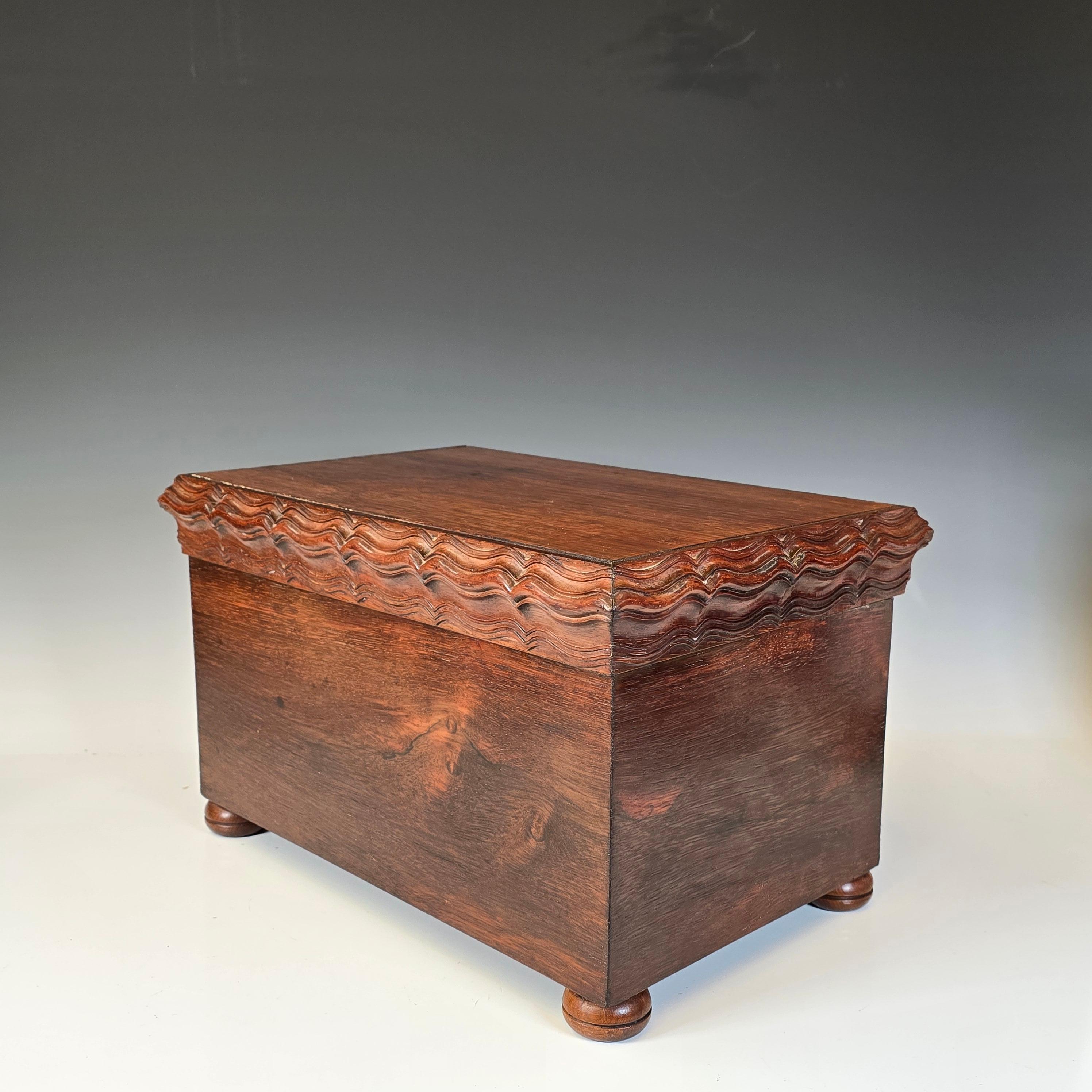 Impresionante caja chapada en palisandro de Brasil de hacia 1940.   La caja tiene una tapa con bisagras y una gran moldura de estilo ondulado holandés que rodea la caja, todo tallado en palisandro macizo.   La caja en sí está fabricada con