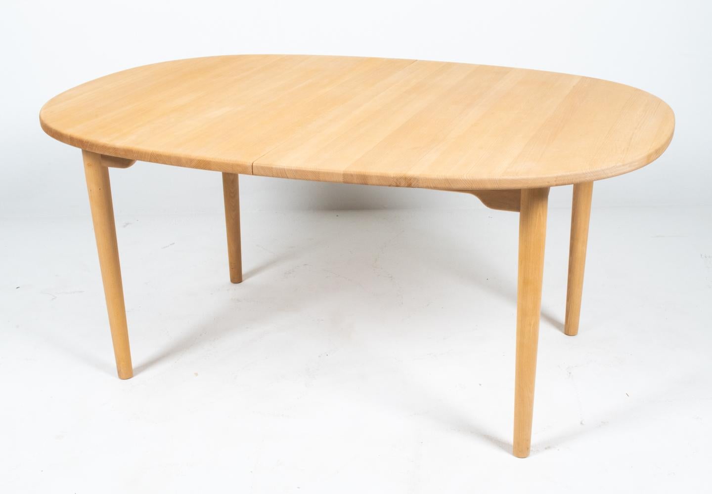 Epitomizing the defining principle of Scandinavian mid-century design, the seamless melding of purposeful utilitarian usage and typically sleek minimalist style, this dining table features an attractively simple top with rounded corners and chic
