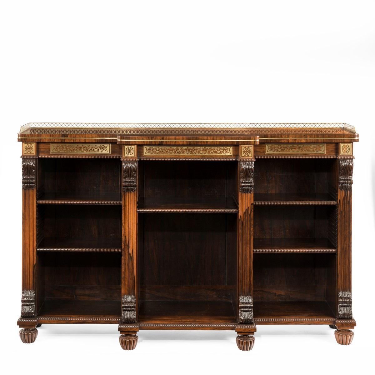 A Regency rosewood breakfront open bookcase attributed to Gillows the shaped top with a brass gallery above a contre-partie boulle-work frieze and four fluted pilasters and three alcoves for five shelves, decorated with brass stringing, solid