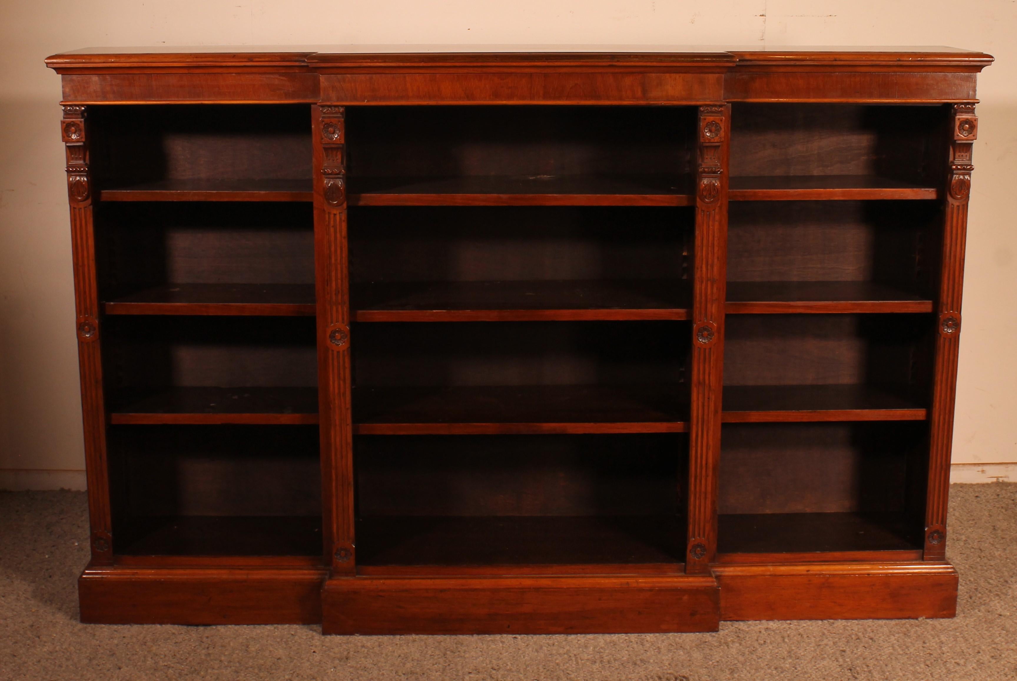 Elegant 19th century mahogany open bookcase from England called Breakfront since it has a forward central section.
It is rare to find a large model with a breakfront that creates movement
uprights decorated with grooves and flowers

Original