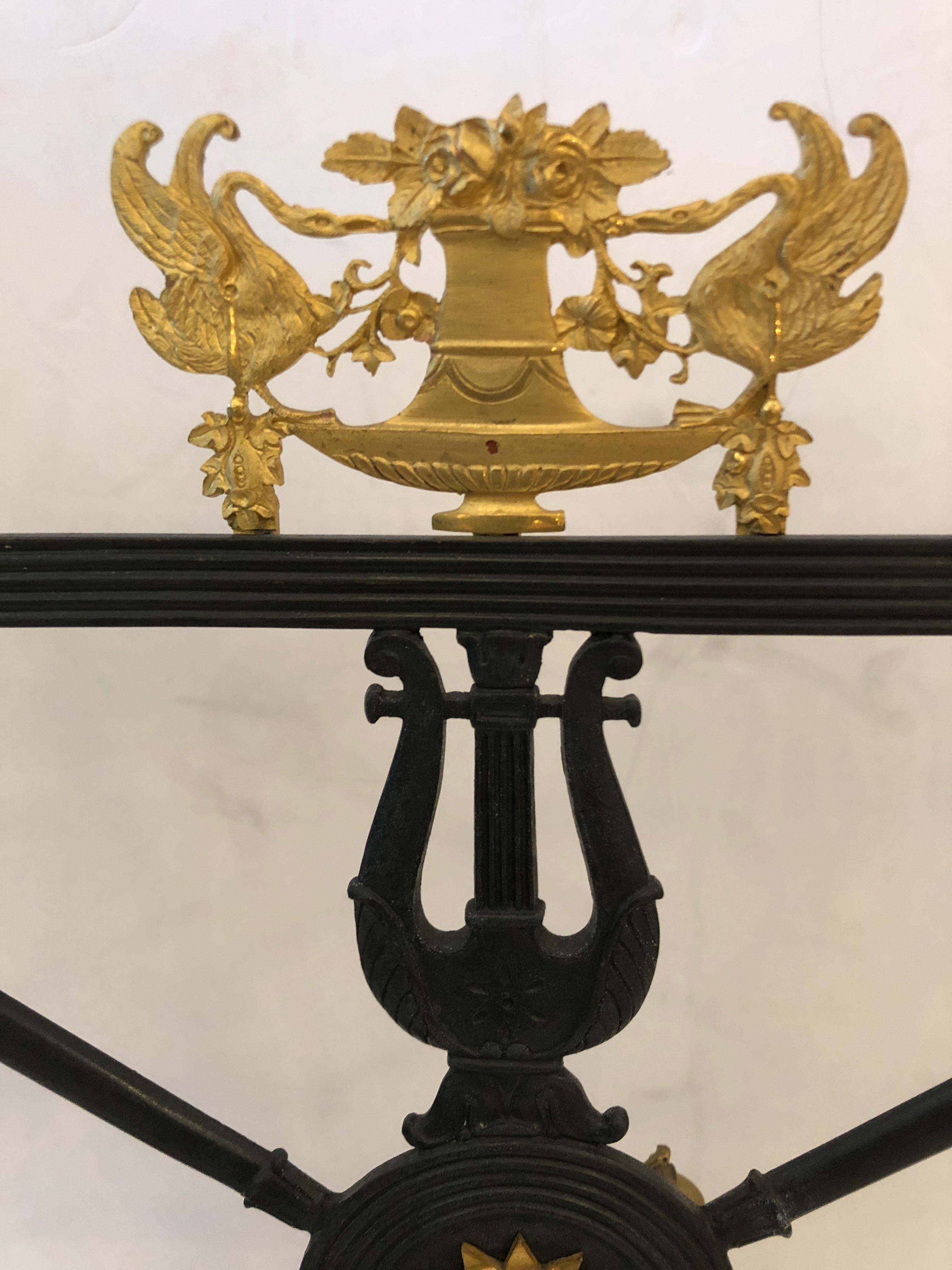 A breathtaking bronze doré neoclassical bookstand that's a true work of art, having contrasting dark bronze and gold embellishments including lyres, swans, a classical sunburst face, scrolls and acanthus leaves, with fluted column resting on a