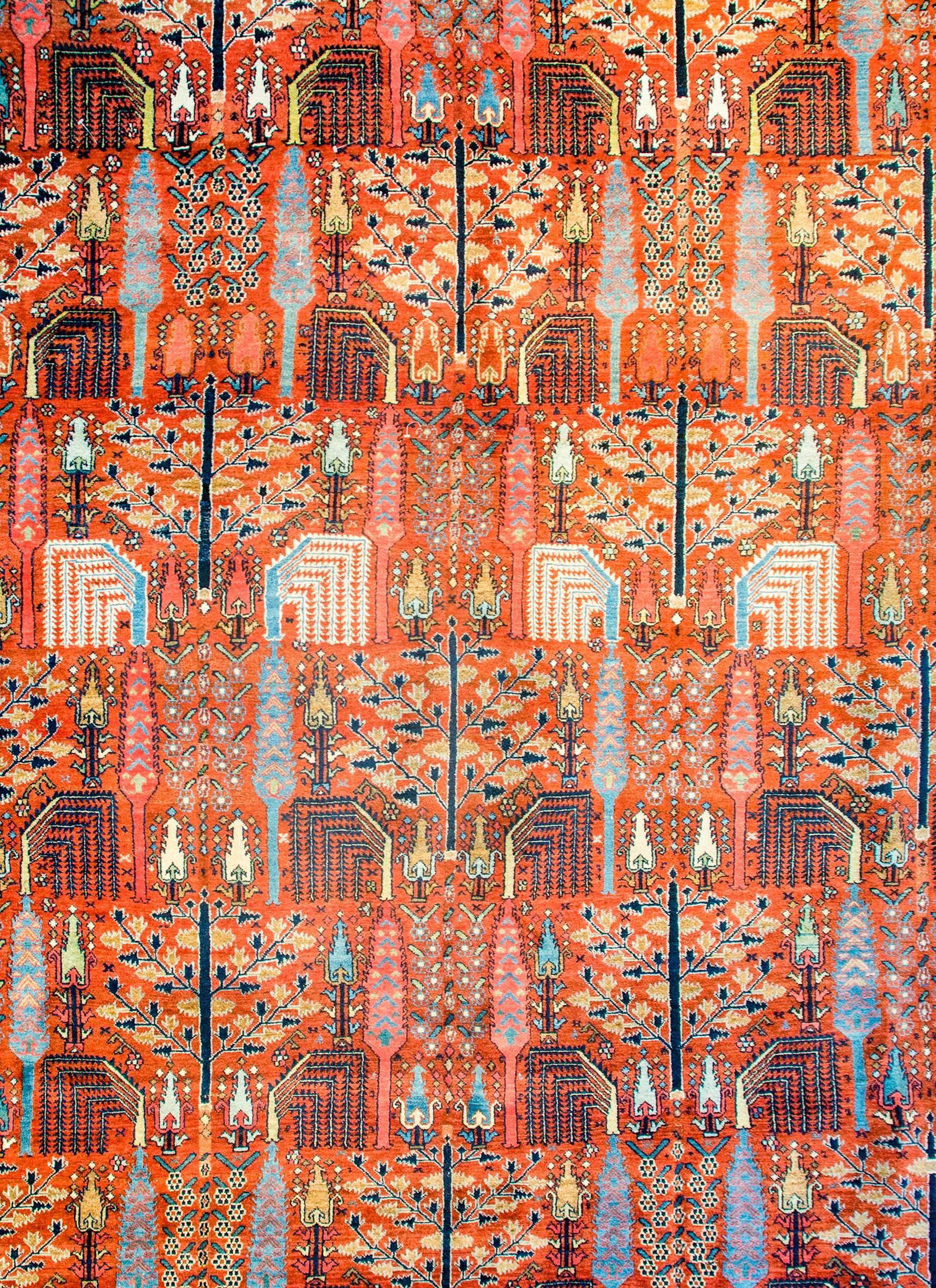 Ein atemberaubender persischer Bidjar-Teppich aus dem frühen 20. Jahrhundert mit wiederkehrenden Weiden, Zypressen und anderen Bäumen des Lebens
muster aus indigo-, gold- und weißfarbener Wolle auf einem leuchtenden korallenfarbenen Hintergrund.