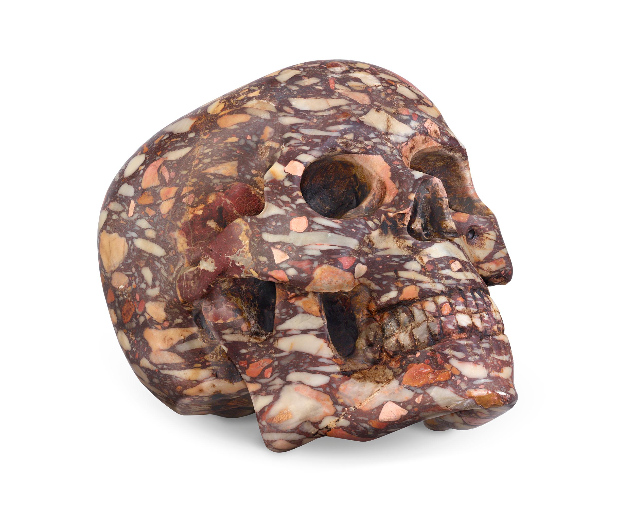 This fascinating carving of a human skull is formed from a specimen of Breccia di Skiros, a dynamic, multicolored marble quarried in Italy. This exceptionally detailed example of lapidary work is magnificently crafted, from the well-formed teeth to