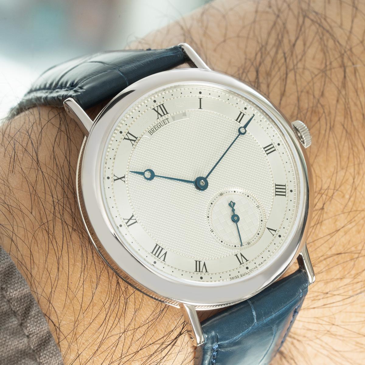 A Breguet Classique 40mm wristwatch in white gold. Featuring a silvered guilloche dial with Roman numerals, an off-centre small seconds dial, and a secret Breguet signature . The watch also features blued steel Breguet hands and a smooth fixed white