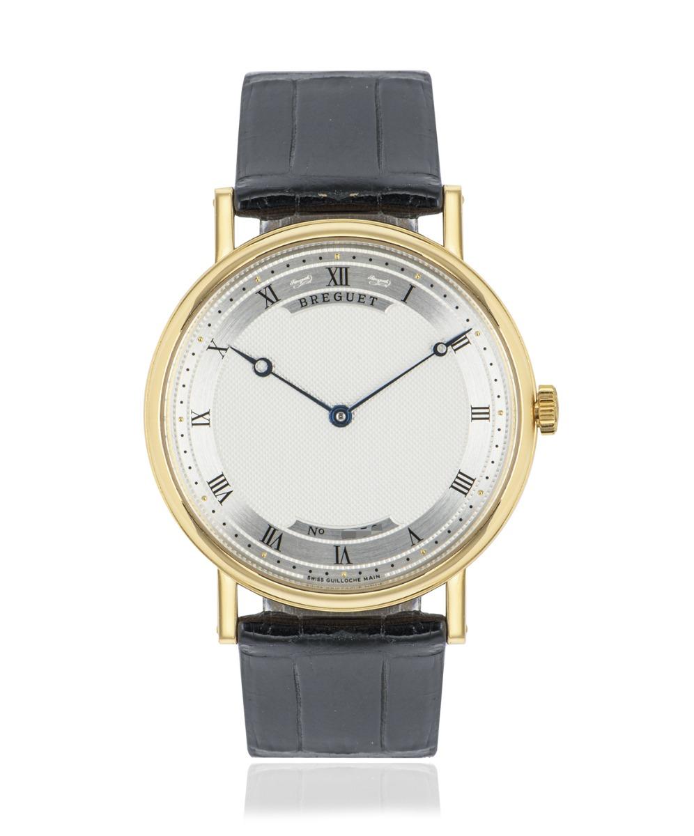 A men's Classique wristwatch crafted 38mm in yellow gold by Breguet. Featuring a silvered dial with a textured guilloche pattern finish and blued steel hands. Features a smooth fixed yellow gold bezel with a coin edge finish known among the Breguet