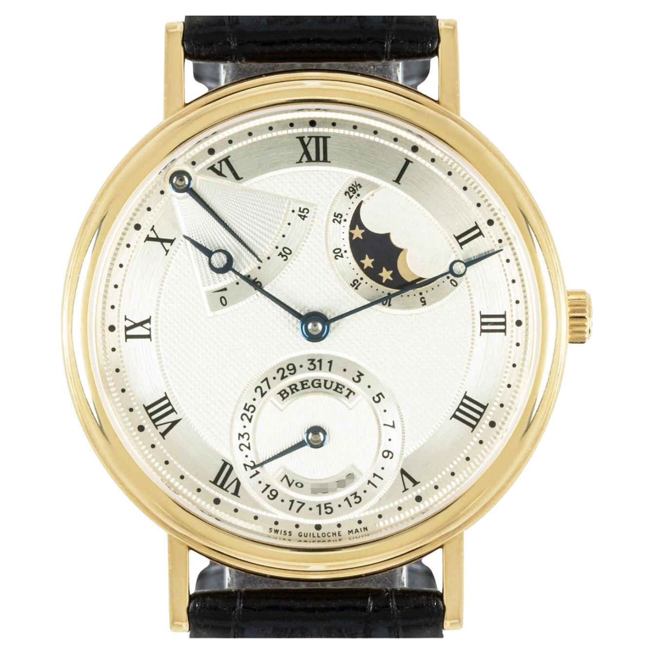 A Classique wristwatch in yellow gold by Breguet. Featuring a silvered dial with a textured guilloche pattern, a power reserve as well as a moon phase indicator and a yellow gold bezel.

Equipped with a generic black leather strap and a yellow gold