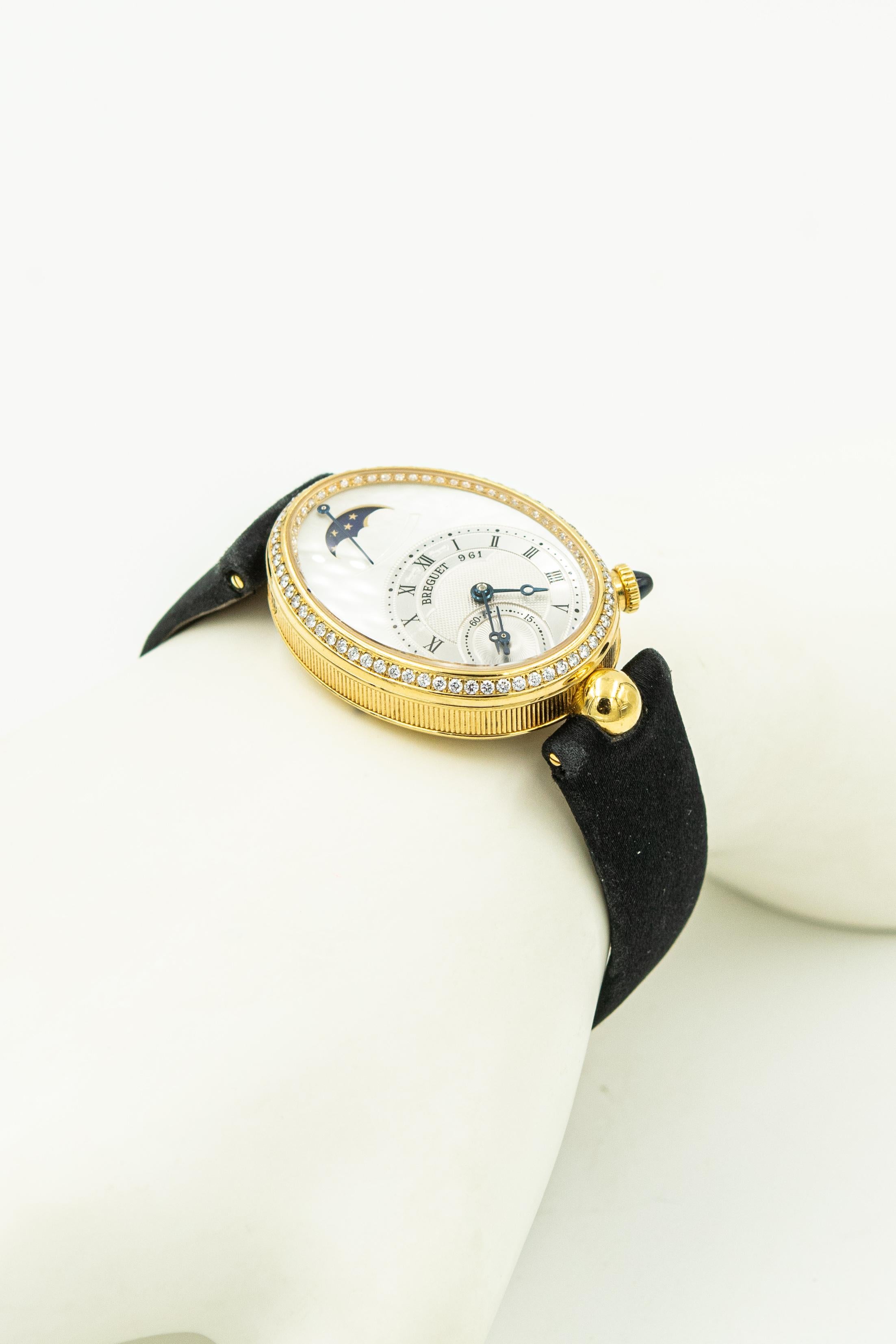 Breguet Reine de Naples 18k Yellow Gold with Diamond Bezel Ladies Moonphase Wrist Watch.  Reference 8908.  The bezel has 128 white round brilliant diamonds with a total weight estimate 0.83 carats.  The black satin strap has a deployant clasp and