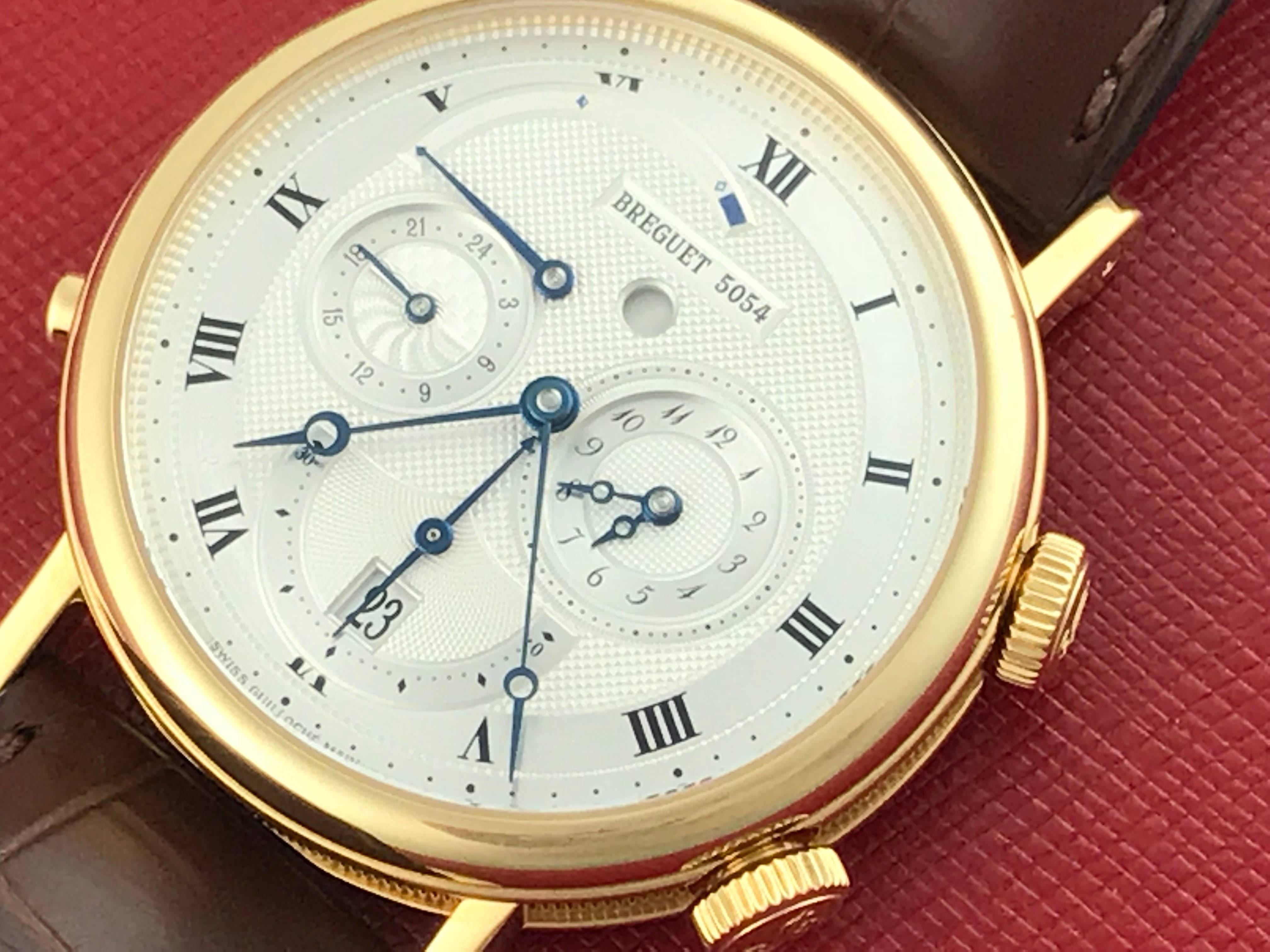 Breguet Classique Model 5707BA/12/9V6 pre-owned men's automatic wrist watch. GMT Alarm; 24 Hour, GMT, Alarm display with Power Reserve Indicator. Tu-tone Silvered textured Dial with black Roman numerals. 18k Yellow Gold round style case with