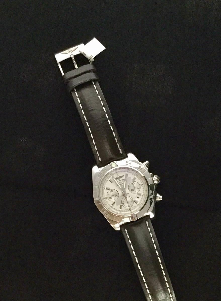 Stainless steel Breitling Chronomat B01 with Silver dial, automatic movement, rotating bezel and Breitling black leather strap.