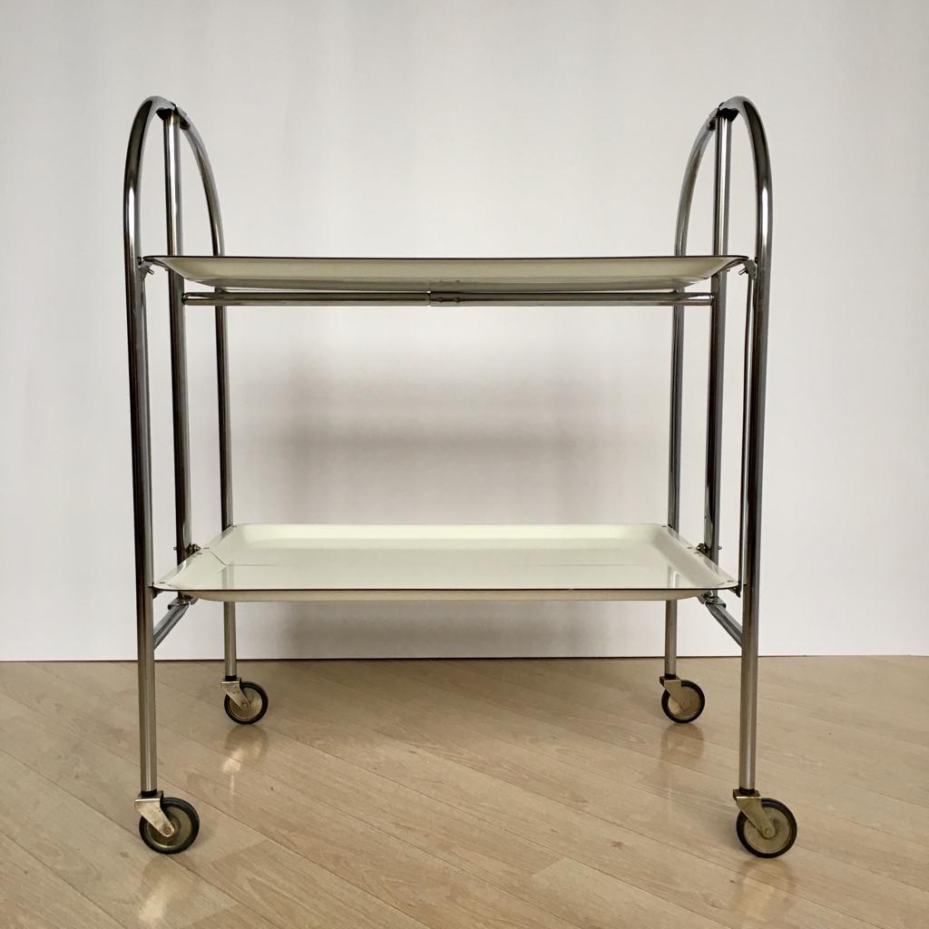 German serving cart famous for its Gerlinol trays. Gerlinol is a pressed veneer, varnished with synthetic resin. Due to this material the trays are very hardwearing and white color is still white despite its age.
You can use it as a shelf folding