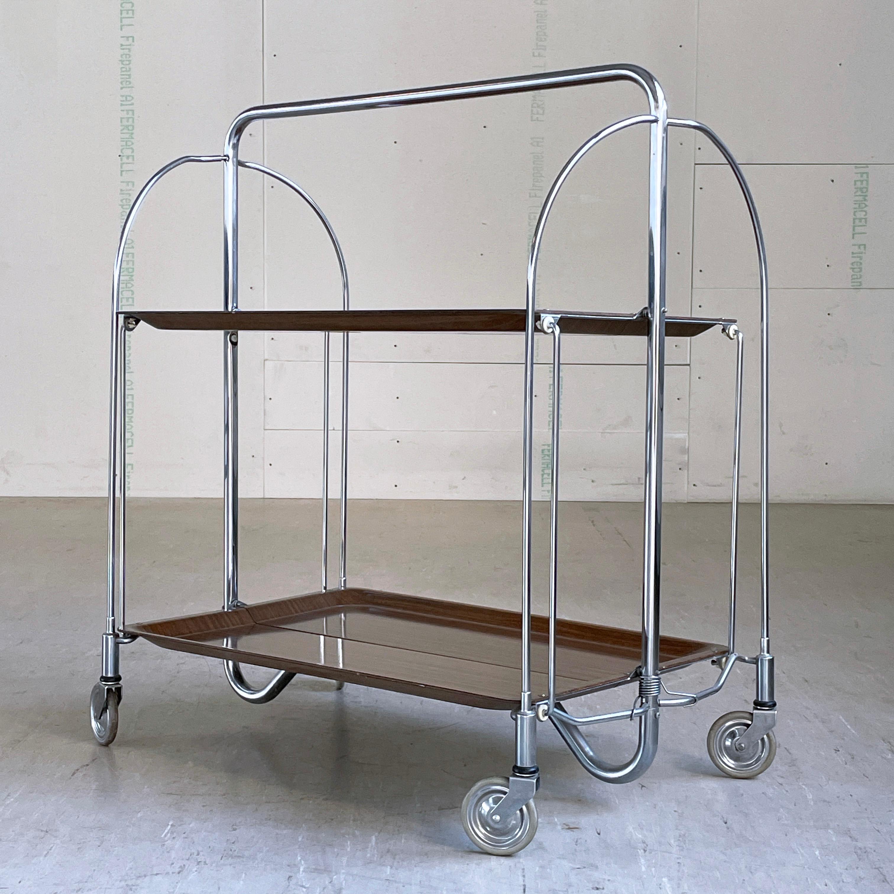 Bremshey & Co. Dinette Serving Trolley. Chromed steel folding frame with wood effect Formica surface. Practical for easy storage and occasional usage.
Producer: Bremshey & Co. (Bremshey Gerlinol) Germany 1970 - 1979
Measurements: Height: 78 cm 