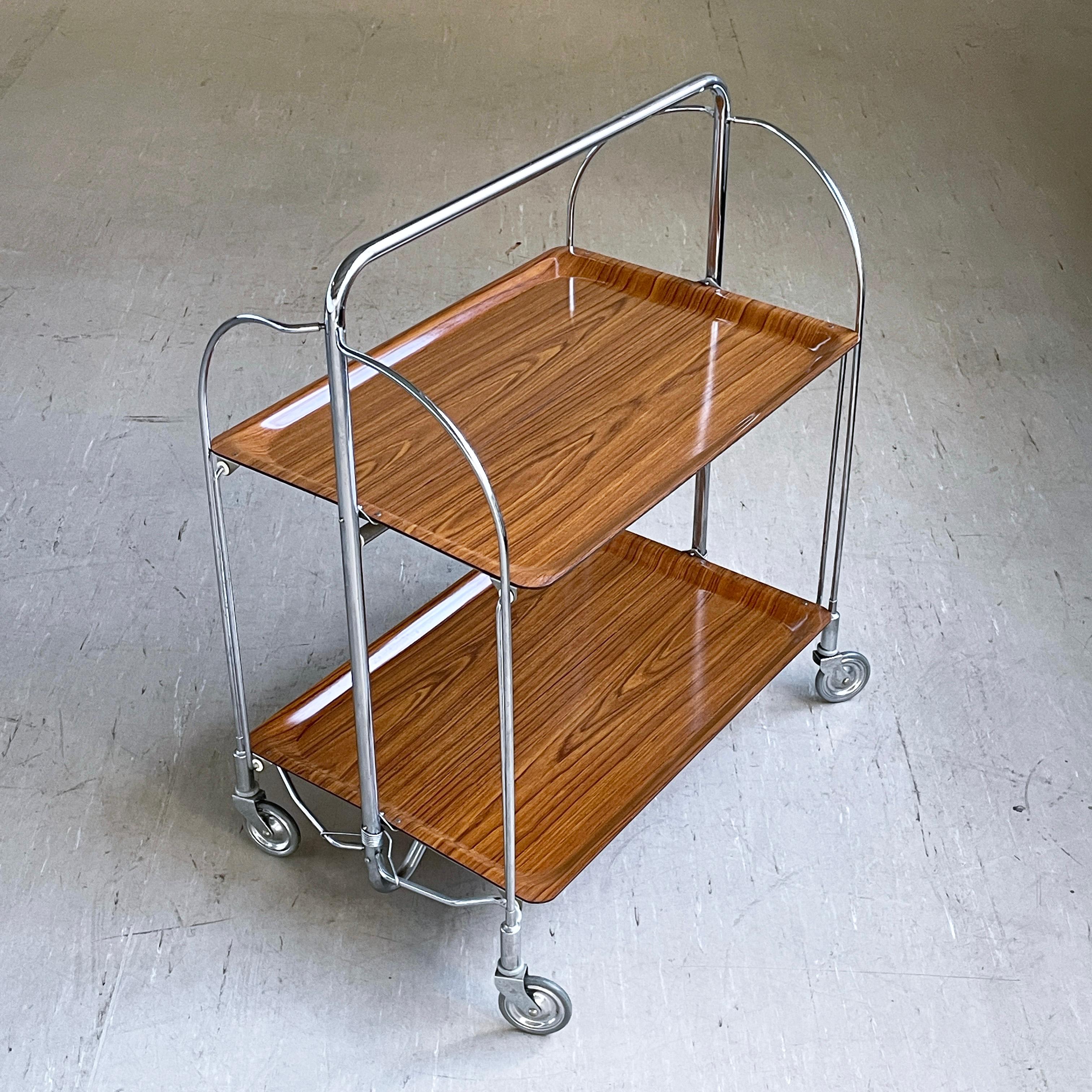 Bremshey & Co. Germany Chromed steel folding frame with wood effect Formica surface. Practical for easy storage and occasional usage.
Producer: Bremshey & Co. (Bremshey Gerlinol ) Germany 1970 - 1979
Measurements: Height: 78 cm  Width: 68 cm  Depth