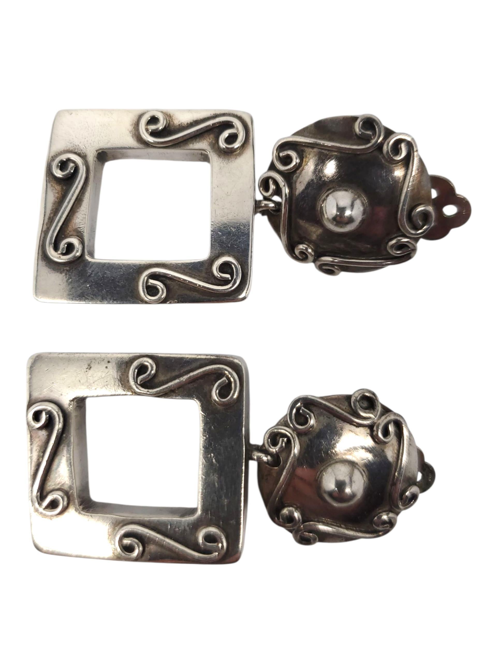 Brenda Schoenfeld Orecchini a clip in argento Sterling Sculpted Square Dangle -

Questi orecchini a clip vintage di Brenda Schoenfeld, datati 1990, sono caratterizzati da pendenti quadrati aperti e dettagli scolpiti a spirale in argento