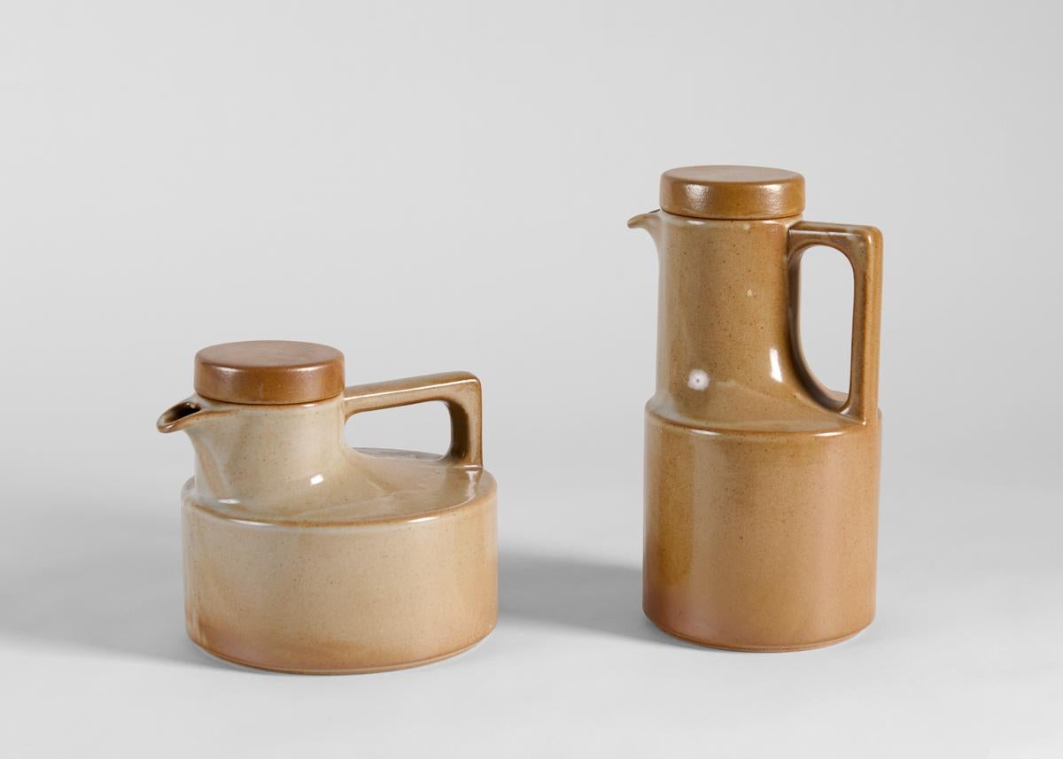 Ces pichets en grès de couleur terre, cuits à haute température, présentent des caractéristiques communes avec des proportions différentes, probablement destinés respectivement au thé et au café. 
Estampillé et 