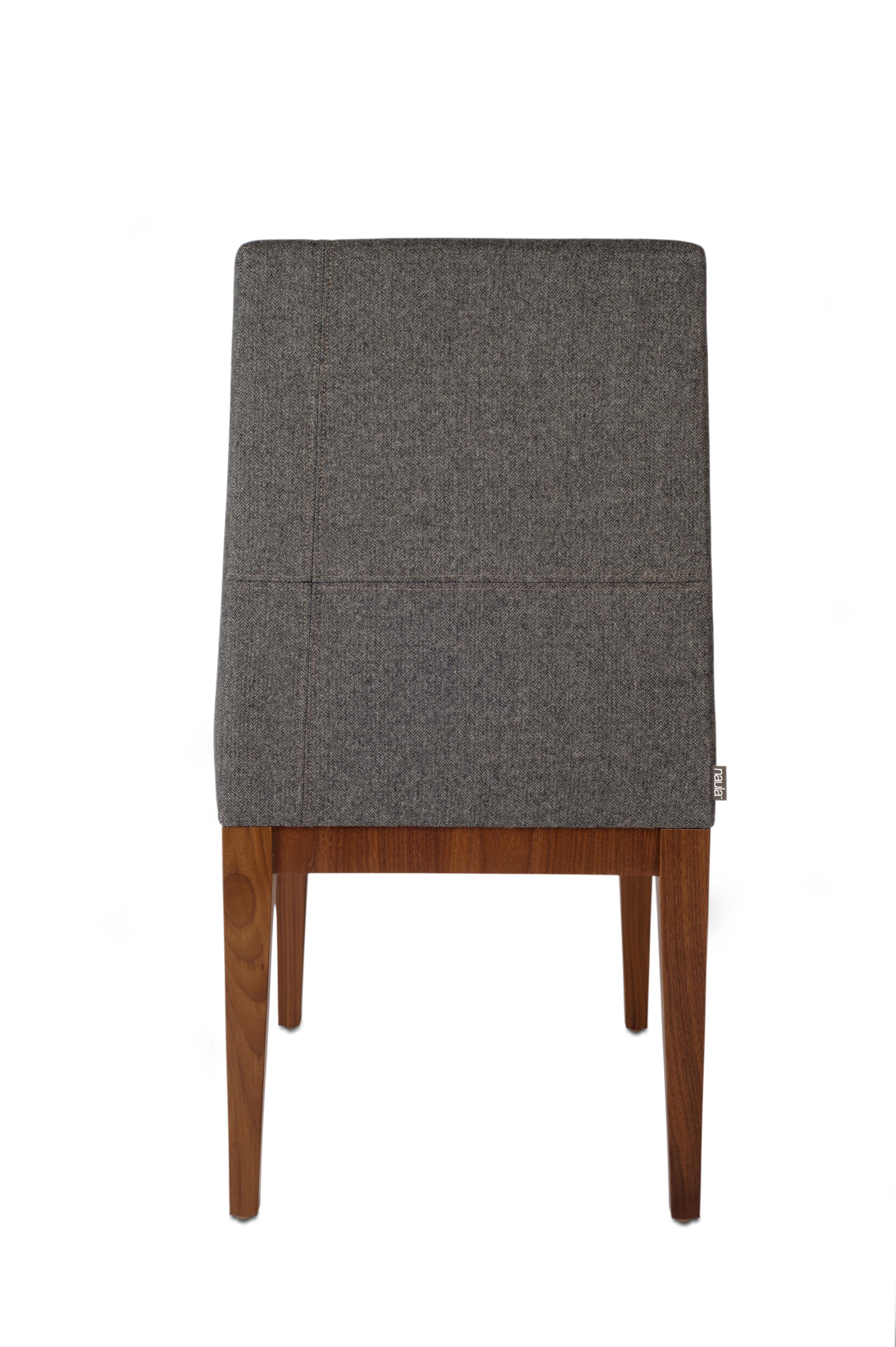 A sleek and modern combination of upholstery and wood, this dining chair is balanced and minimal. Subtle, offset hand-stitching breaks the monotony of the fabric and finishes off a look that sits well at any table.