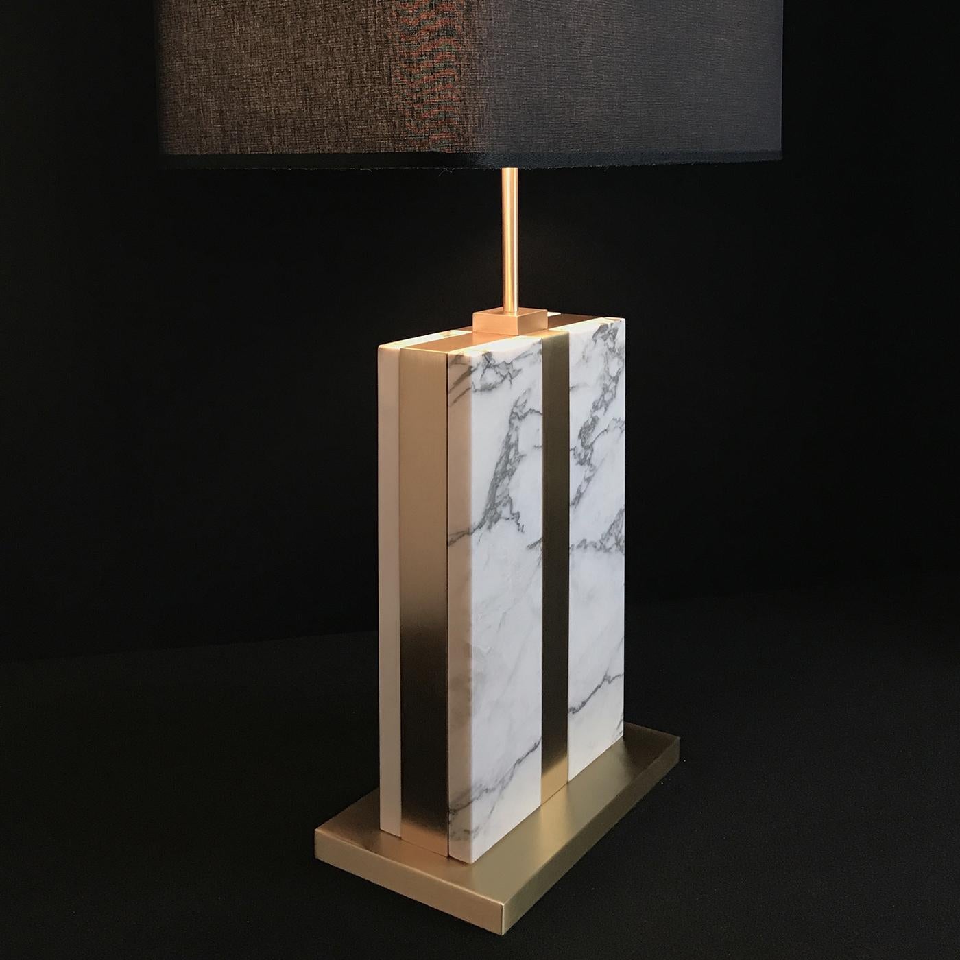 Doubling as a glamorous decorative accent piece and a functional source of light, this refined table lamp will fit perfectly in any room, from the bedroom to an entryway. Featuring a satin-finished brass platform and frame, the stunning Arabescato