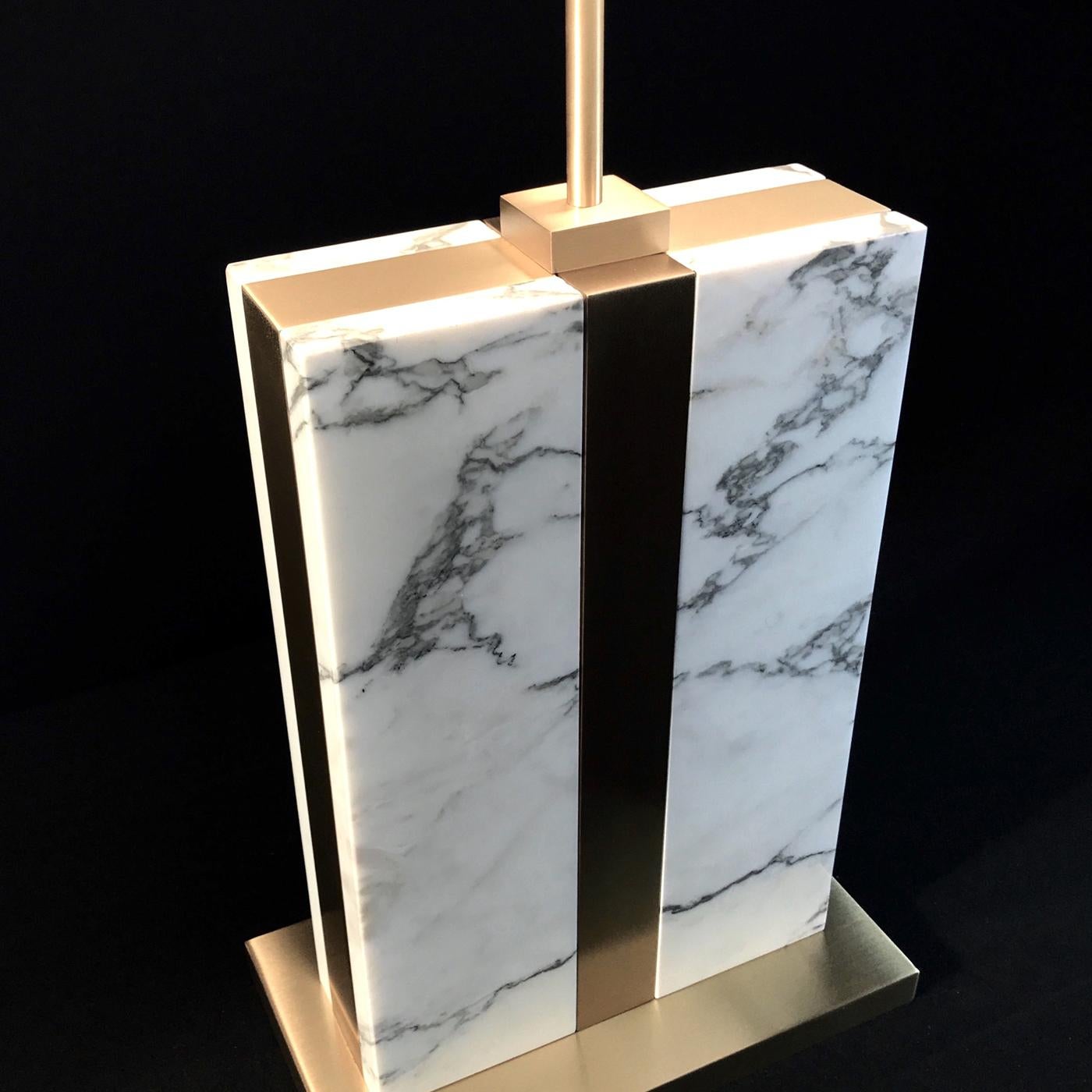 Combining brass and marble in a Classic silhouette, this table lamp's luxurious aesthetic is matched by its timeless elegance. Raised on a square satin brass base, the Arabescato Carrara marble body is held by a satin brass support connected to a