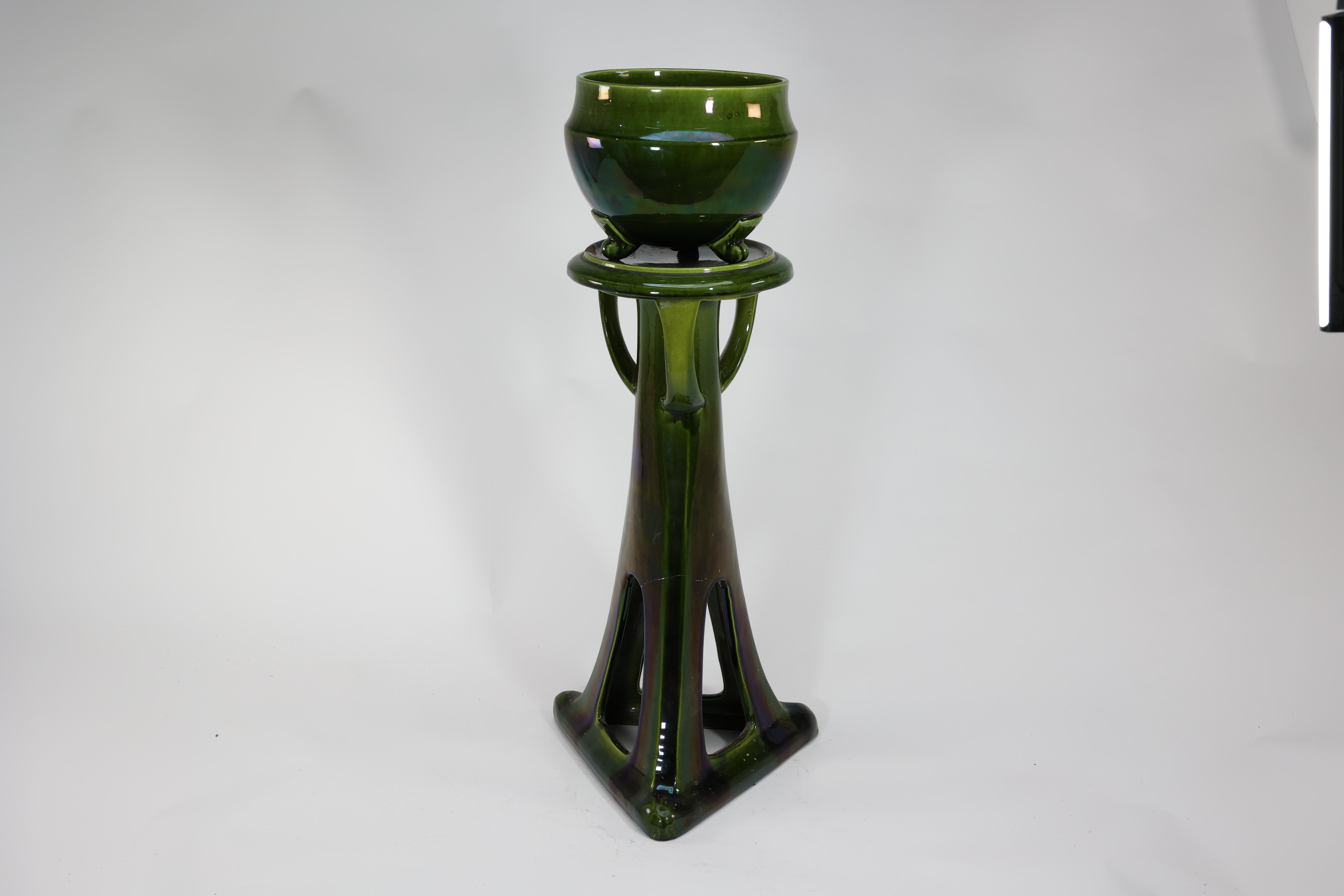 Bretby. An Arts and Crafts green planter and stand both stamped Bretby. The bowl is perfect, the stand has a chip to the top and a hairline crack through one upright but it is completely stable. The nature of its design with three legs to the