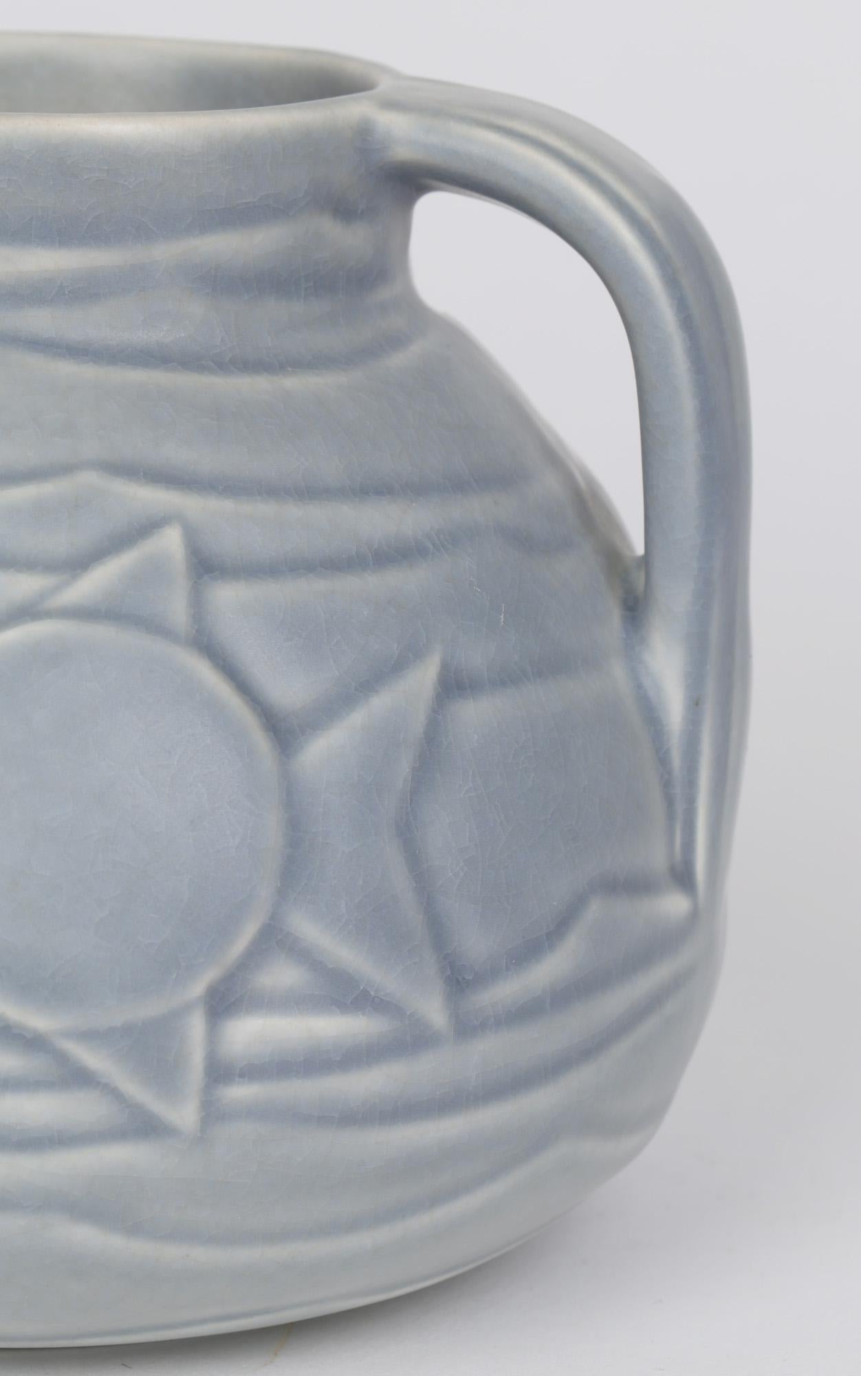 Bretby unusual Art Deco pottery handled jug molded in relief with stylized fish swimming amidst waves dating from around 1930. The squat rounded jug is decorated in pale grey blue glazes and has impressed makers marks to the base along with number