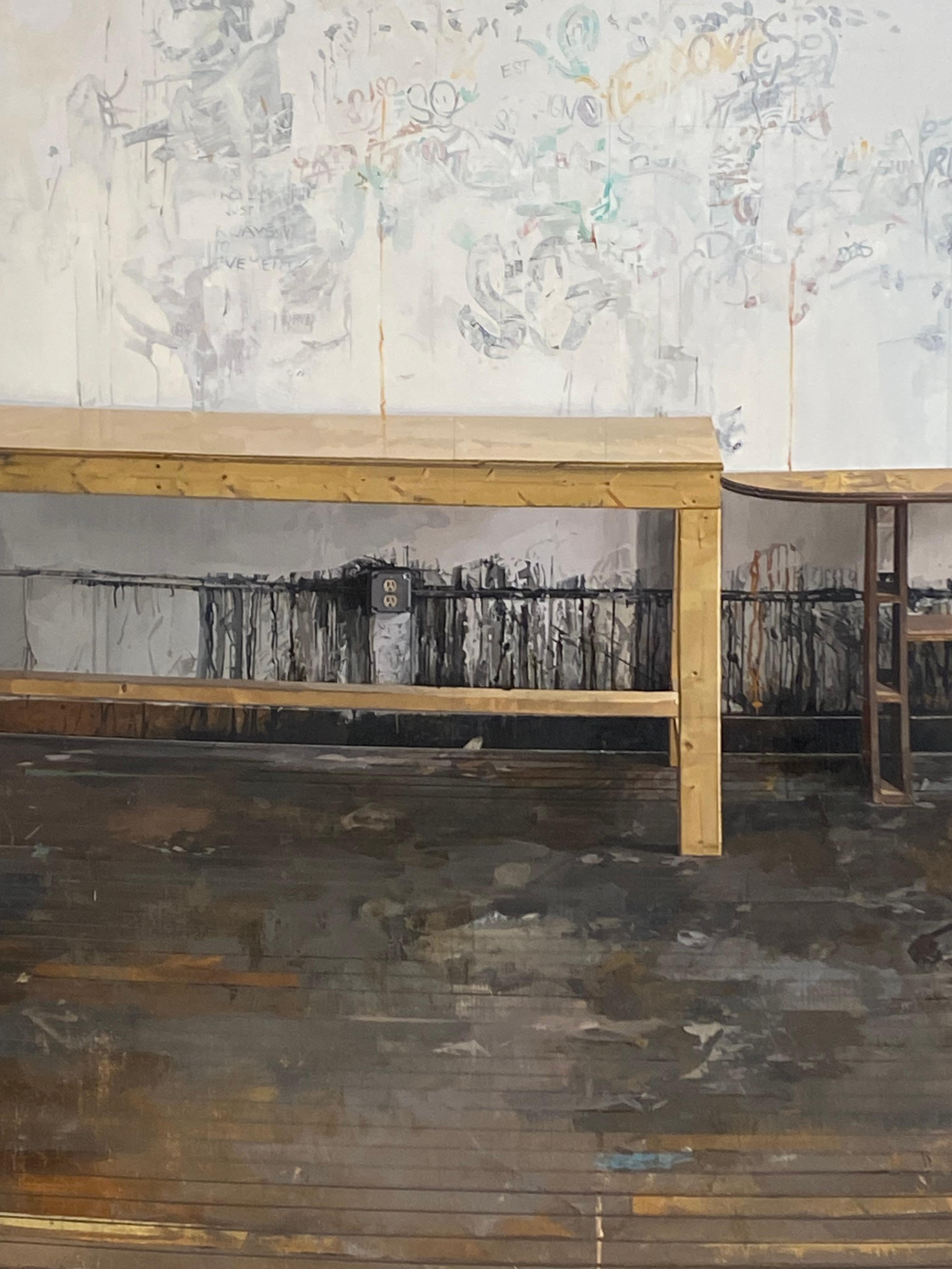 In questo dipinto contemporaneo a olio su tavola, due tavoli di legno si stagliano contro una parete bianca, segnata da segni di opere d'arte passate, nel tranquillo studio di un artista. Il calore del pavimento in legno duro marrone dorato