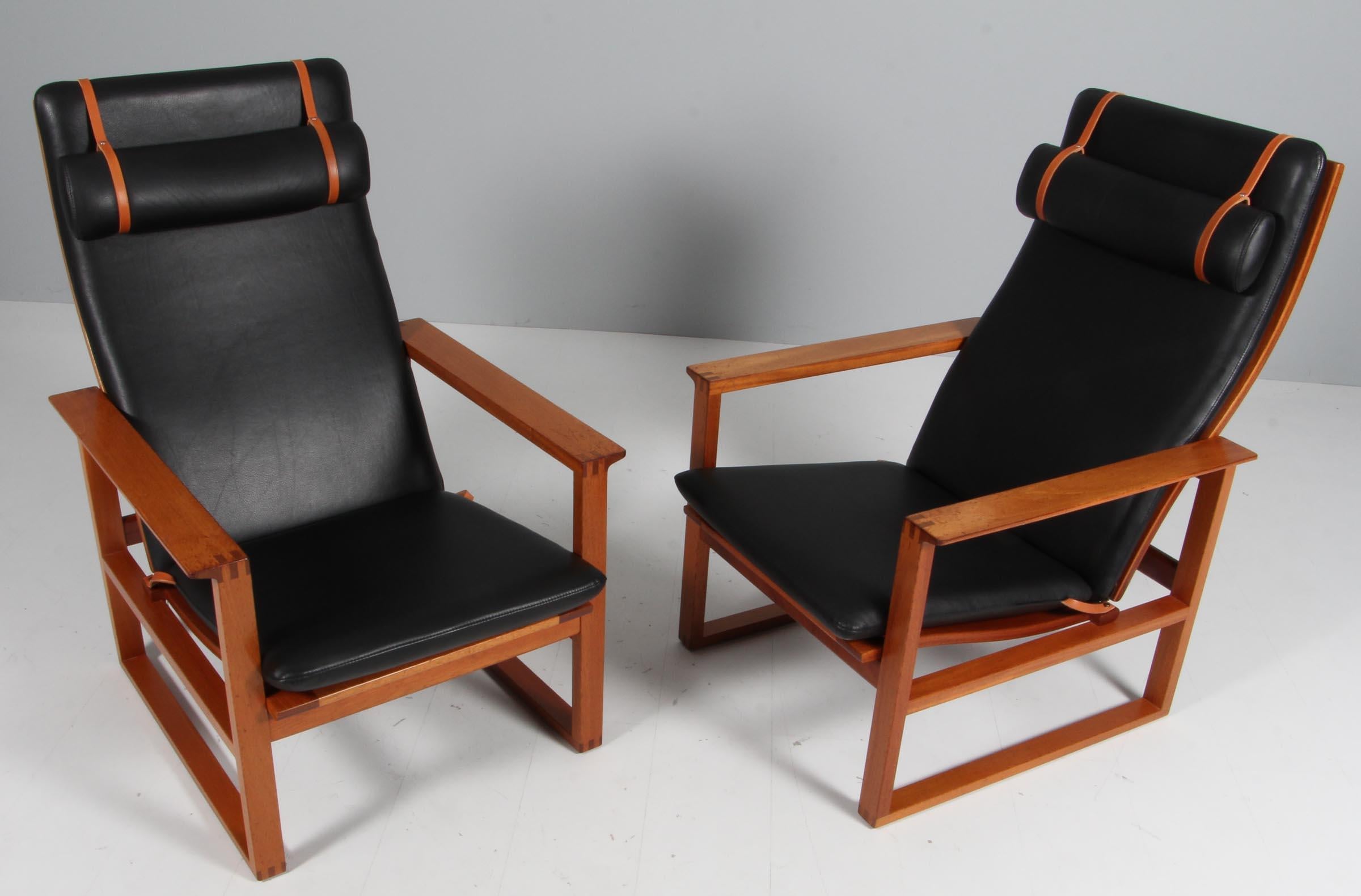 A Børge Mogensen lounge chairs designed in 1956 model number 2254 for Fredericia Stolefabrik. Cubical frames made of solid mahogany with finger joints and cane. 

Reupholstered in black leather. The seat cushion can be fixed with a leather strap