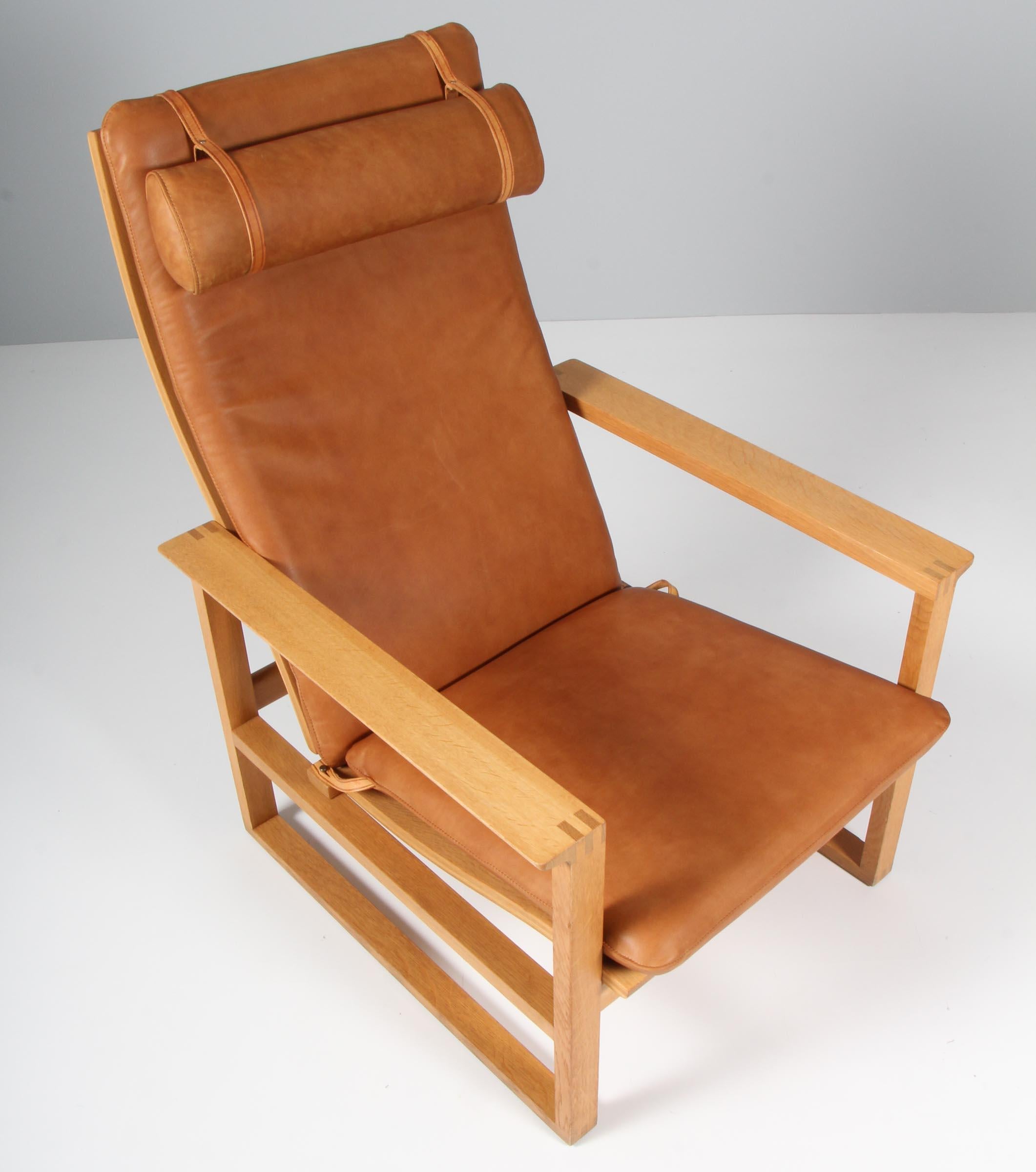 A Børge Mogensen lounge chairs designed in 1956 model number 2254 for Fredericia Stolefabrik. Cubical frames made of solid oak with finger joints and cane. 

New upholstered with cognac vintage aniline leather. The seat cushion can be fixed with a