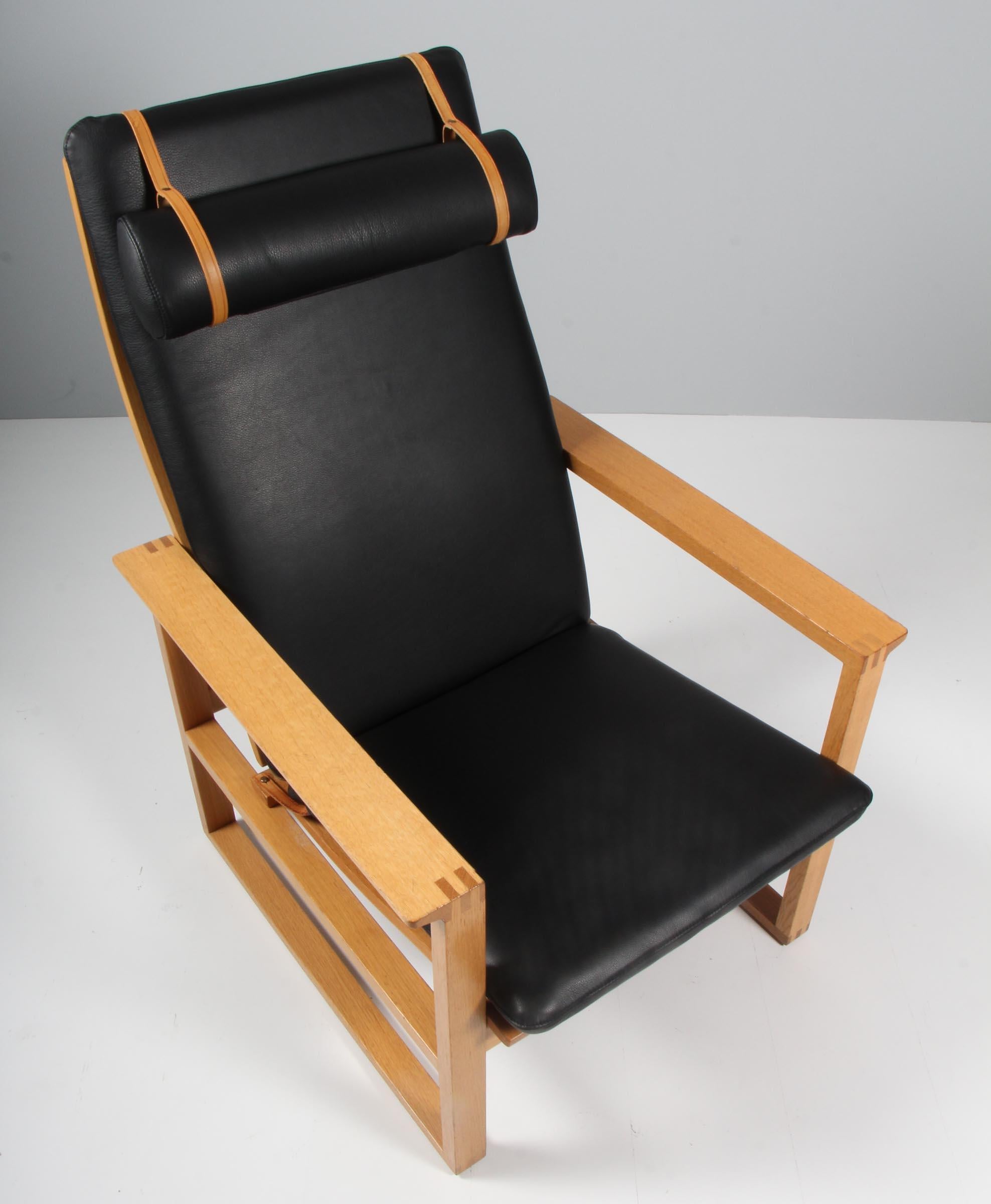 A Børge Mogensen lounge chairs designed in 1956 model number 2254 for Fredericia Stolefabrik. Cubical frames made of solid oak with finger joints.

New upholstered with black aniline leather. The seat cushion can be fixed with a leather strap