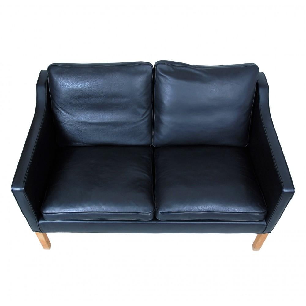 Børge Mogensen 2322 2-Sitzer-Sofa mit schwarzem Bisonleder und Eichenbeinen. Das Sofa hat eine Reihe von Gebrauchsspuren in Form von leicht patiniertem Leder sowie Abplatzungen und Farbunterschiede an den Beinen.