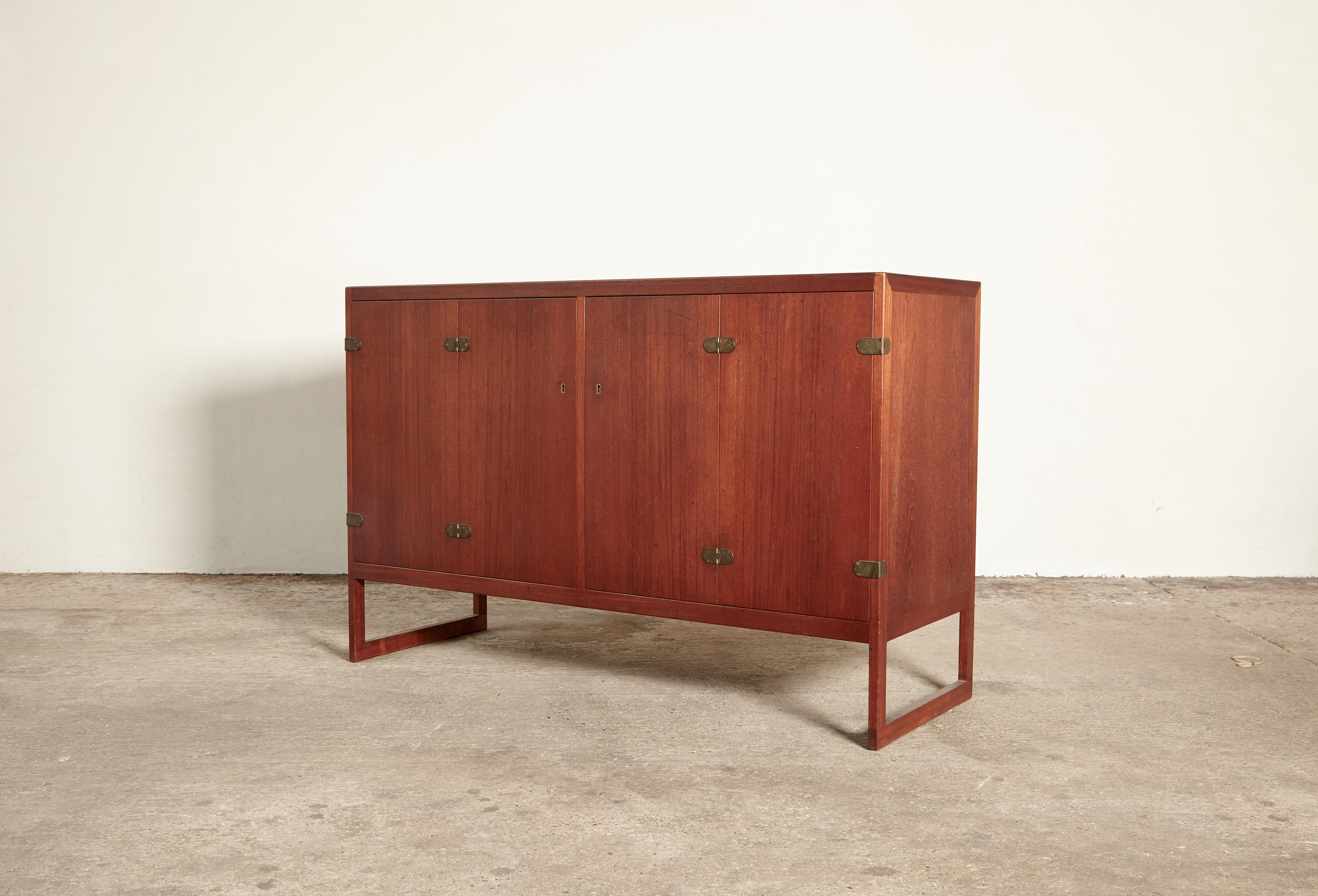 Rare cabinet or sideboard in teak with brass details designed by Børge Mogensen for P. Lauritsen & Søn, 1957, Denmark. Features two bi-fold doors concealing two adjustable shelves and four drawers in oak. With one key.   Ships worldwide - please
