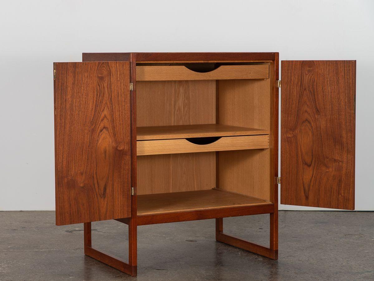 Danish Modern storage cabinet in teak, designed by Borge Mogensen for P. Lauritsen and Son. Contrasting with the warm wood, the polished brass hardware adds a touch of elegance to the understated design. Delightful petite size allows for use in