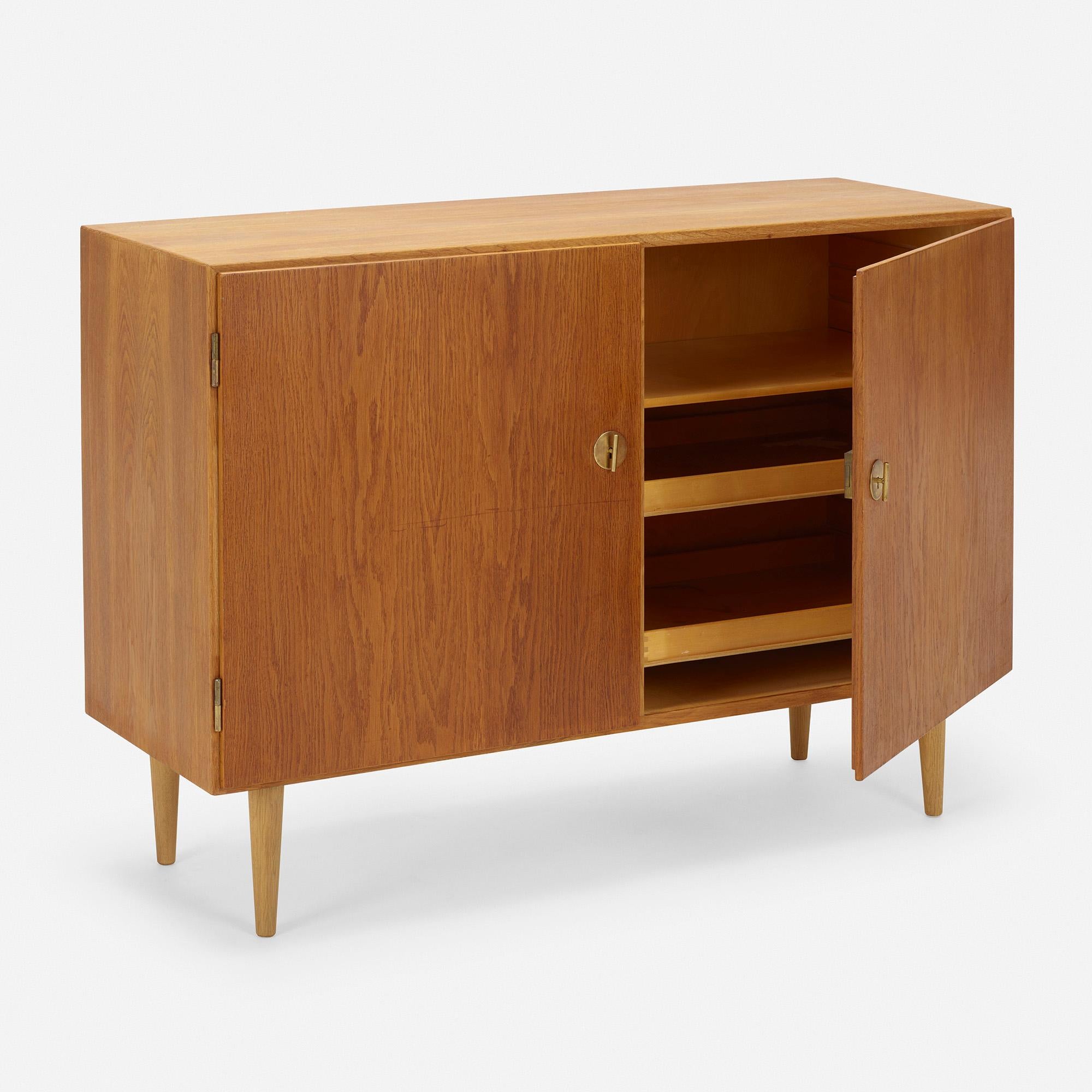 Made by: C.M. Madsens Fabrikker for FDB Møbler, Denmark, c. 1945

Material: oak, brass

Size: 48 w × 18.25 d × 34.5 h in

Description: Cabinet features two doors concealing adjustable shelving and drawers. Sold with a total of four drawers and two
