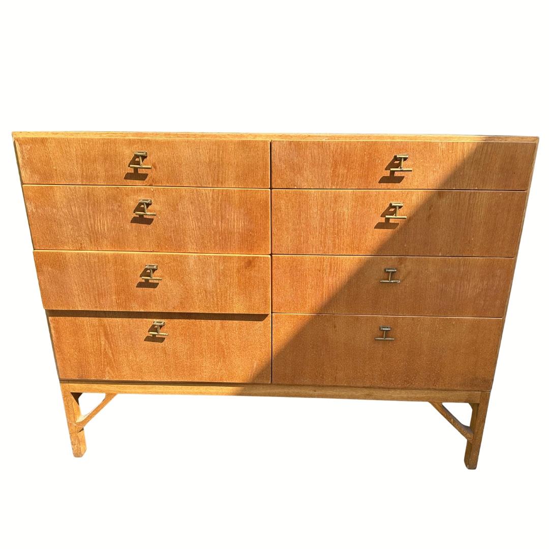 Kommode des dänischen Architekten Børge Mogensen (1914-1972) aus massiver und furnierter Eiche mit Seifenbehandlung. Das klassische Aufbewahrungsmöbel hat 8 Schubladen, die mit Schubladengriffen aus Messing versehen sind. Der Chinabein-Sockel aus
