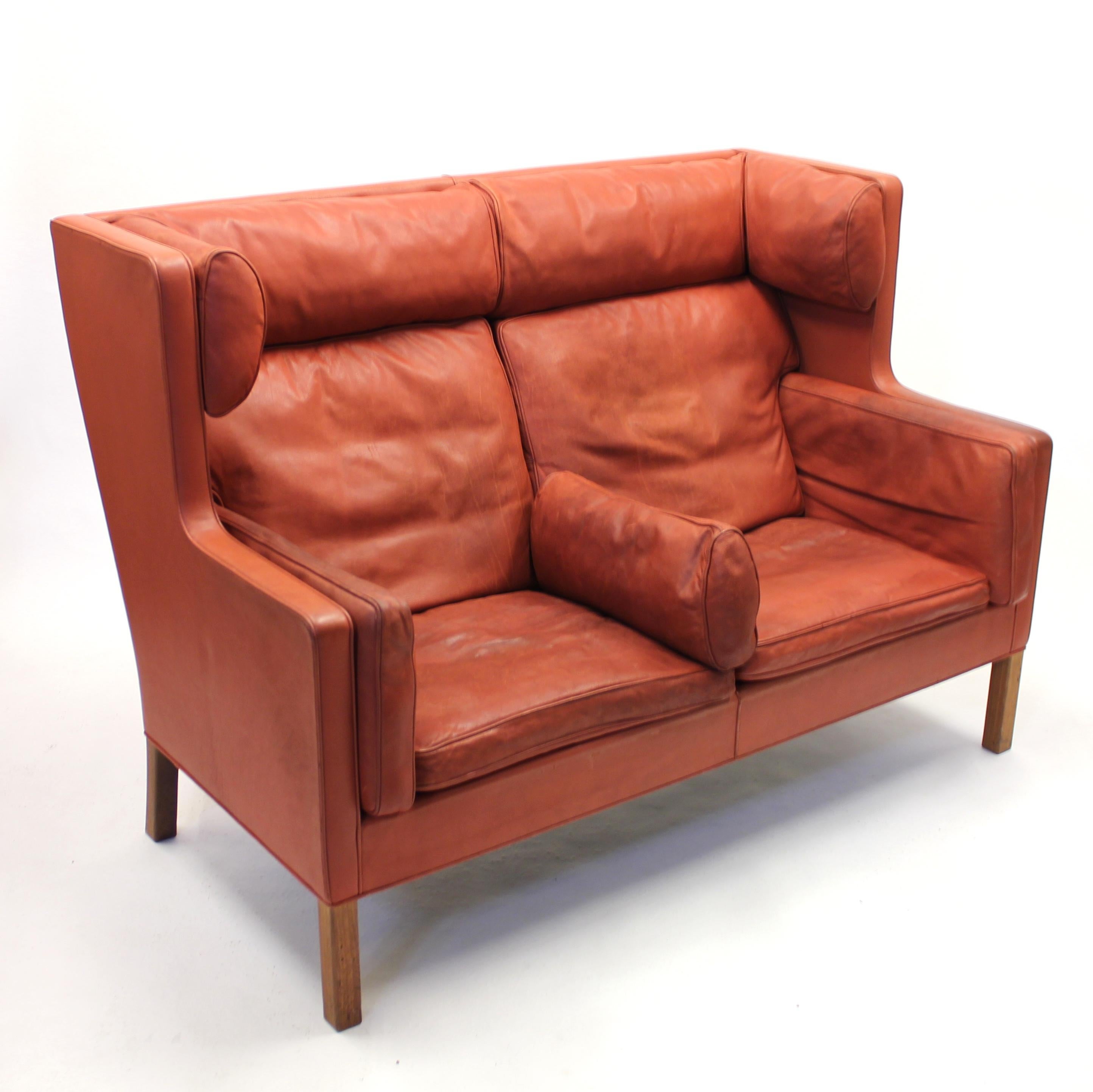 Two seater leather coupe sofa, model 2192, designed by Børge Mogensen for Frederica Furniture. Made in the 1980s. Upholstery in red / brown / cognac coloured leather on teak legs. This sofa has quite a bit of honest patina, weathered look and some