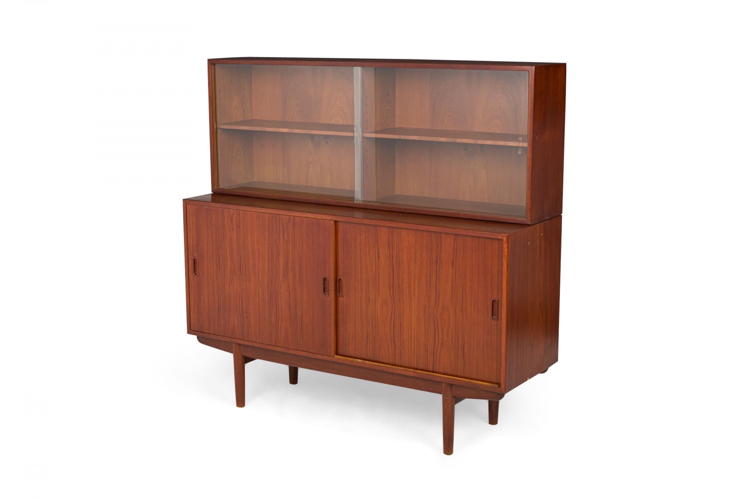 Danish mid-century teak serving cabinet / china hutch with a rectangular lower cabinet with two sliding doors supporting, a two shelf upper china cabinet with sliding glass doors, resting on four tapered teak legs. (BØRGE MOGENSEN)