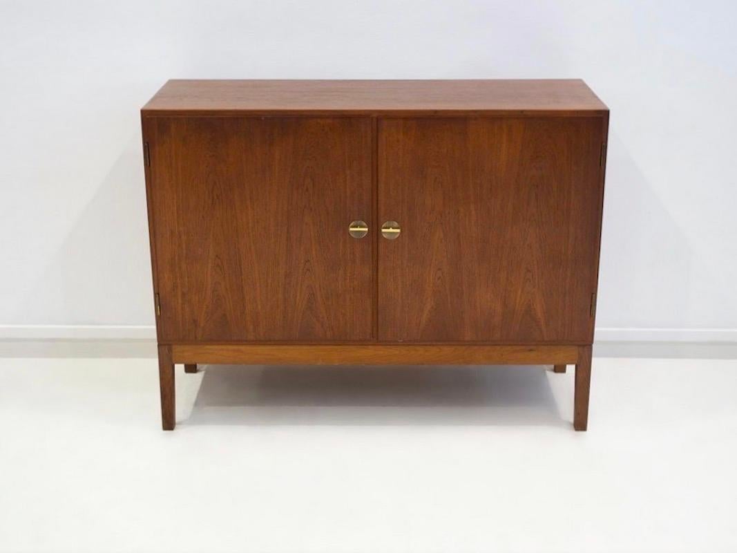 Mobile in teak, successivamente montato su piedi in quercia non originali di colore leggermente più chiaro. Anteriore con due porte. Interno con due ripiani e quattro vassoi estraibili. Prodotto in Danimarca da FDB Møbler. Sono incluse due chiavi