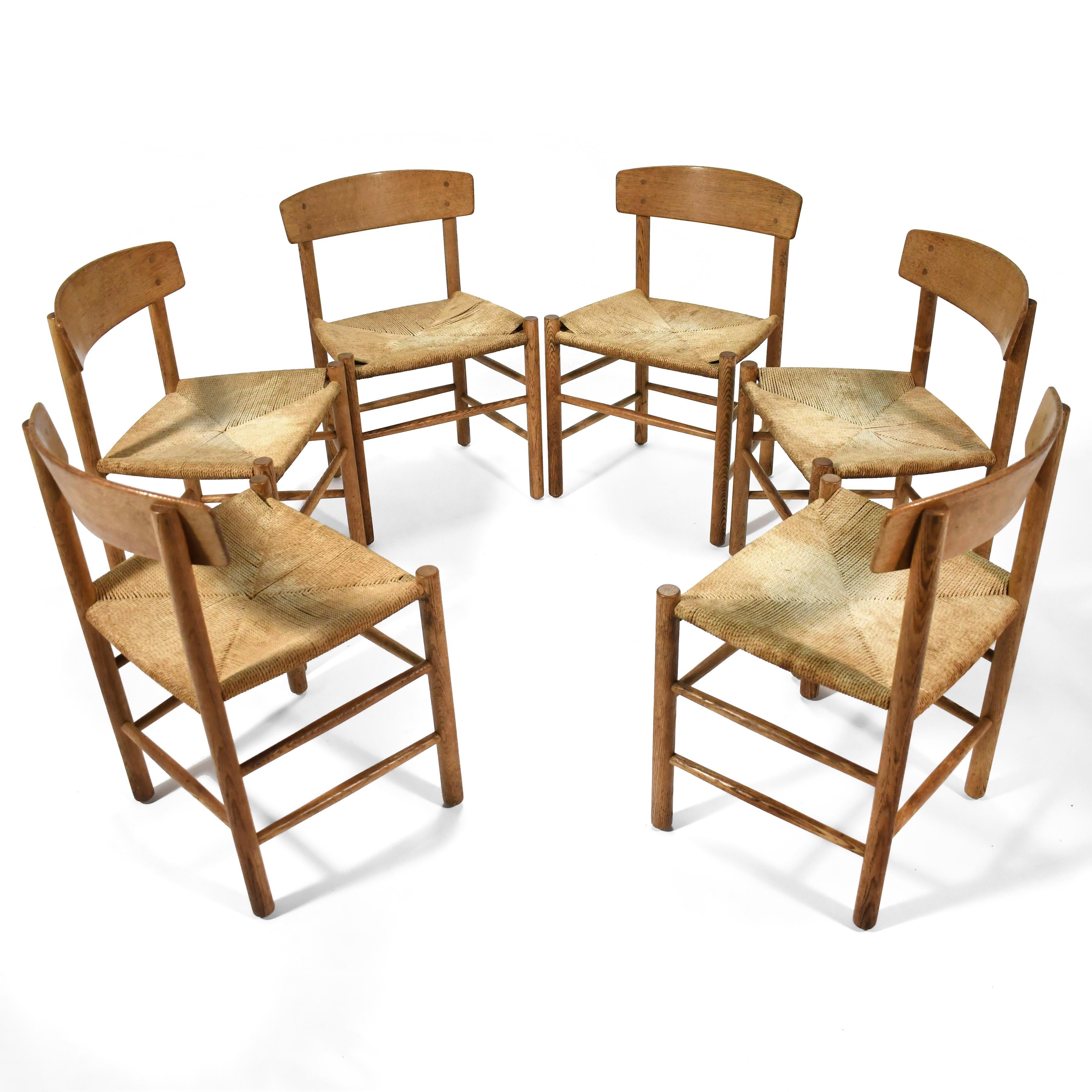 Borge Mogensen's J39 chair design has a shaker style frame of oak with a woven papercord seat. This set of six vintage chairs have a beautiful, rich patina from years of age and use. The frames are all solid, and the seats stable (one chair has a