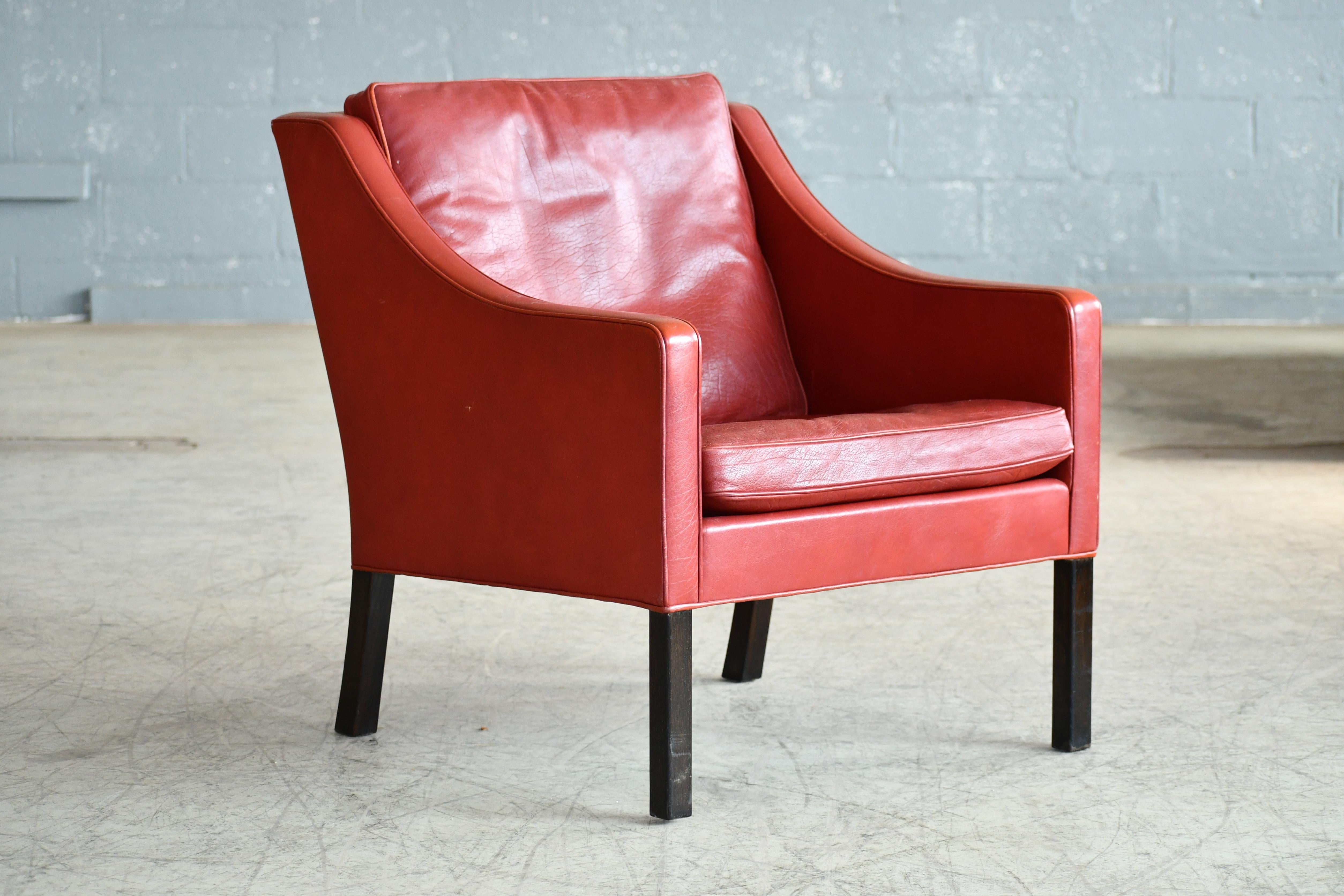 Perennial Børge Mogensen designed lounge chair model 2421 for Fredericia. One of the most elegant Classic midcentury Danish lounge chairs ever made of a design that will just never go out of style. Supple red colored leather with down-filled