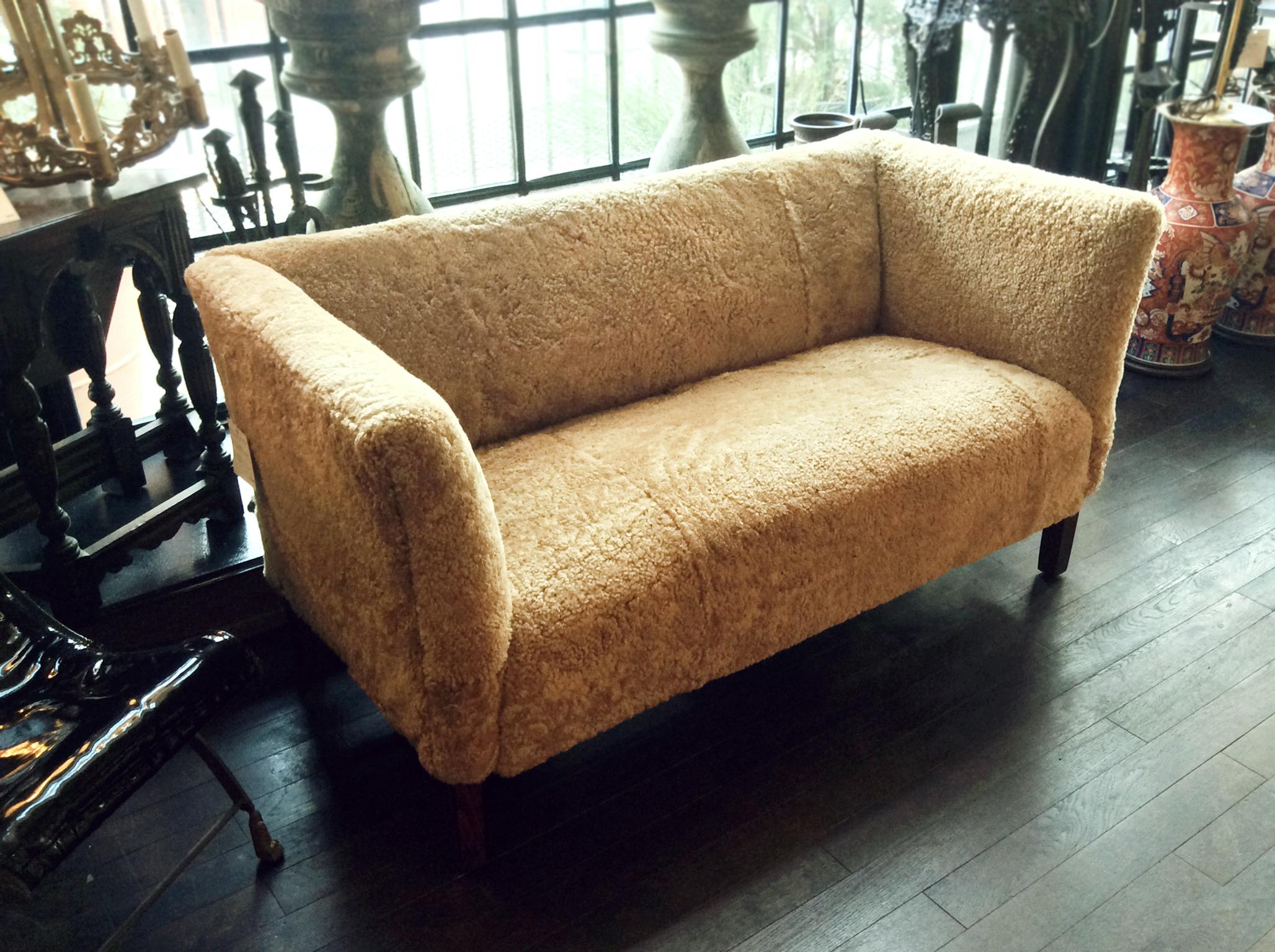 A Danish modern settee sofa designed by Børge Mogensen, manufactured circa 1950s. The settee has been completely reupholstered in a custom honey-toned shearling from Skandilock. This sheepskin is a soft curly texture that accentuates the settee's