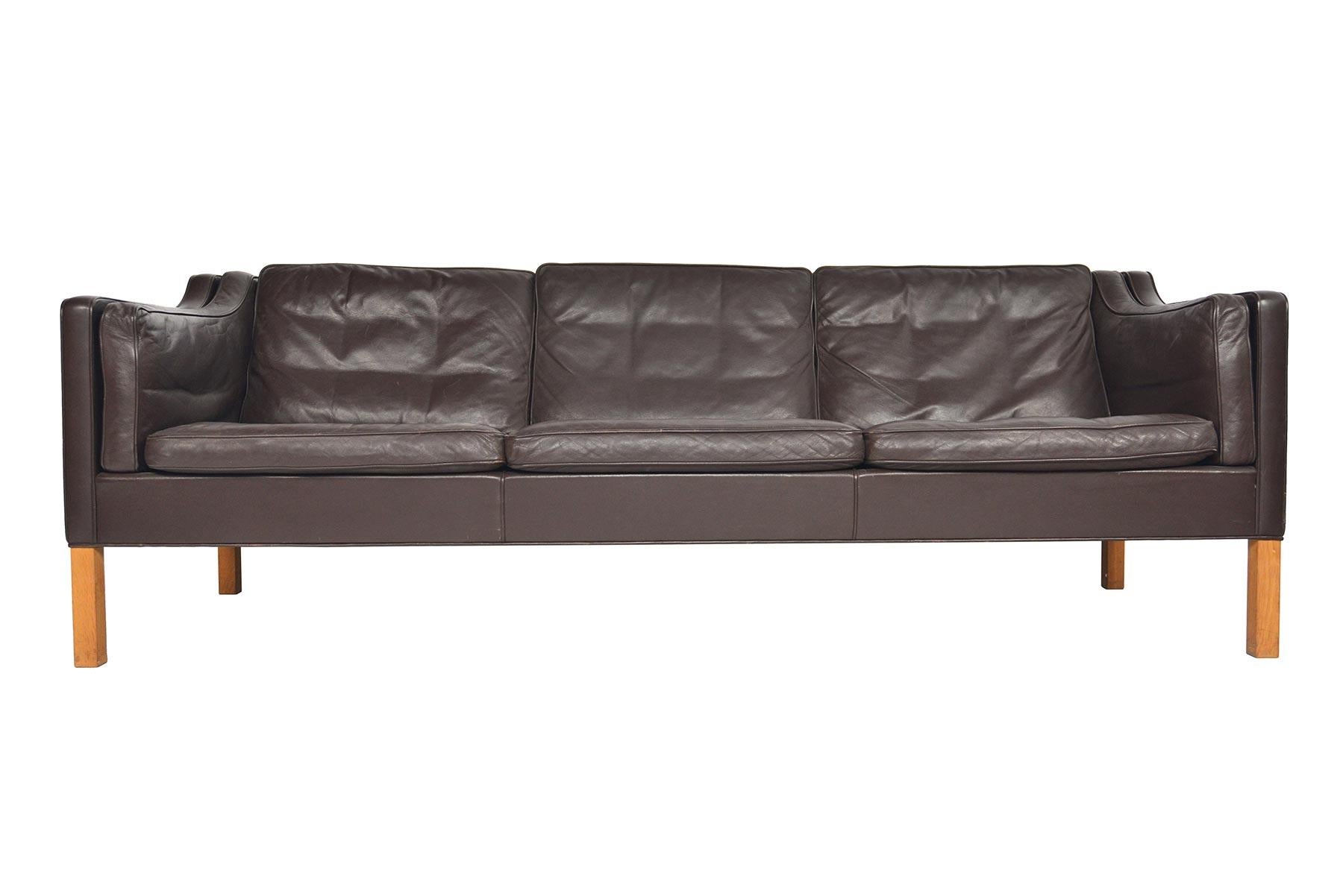 This Danish modern midcentury Model 2213 three-seat brown leather sofa was designed by Børge Mogensen for Frederica Furniture. A staple of modern decor, this piece set a new standard for simplistic, timeless design. This completely original sofa is