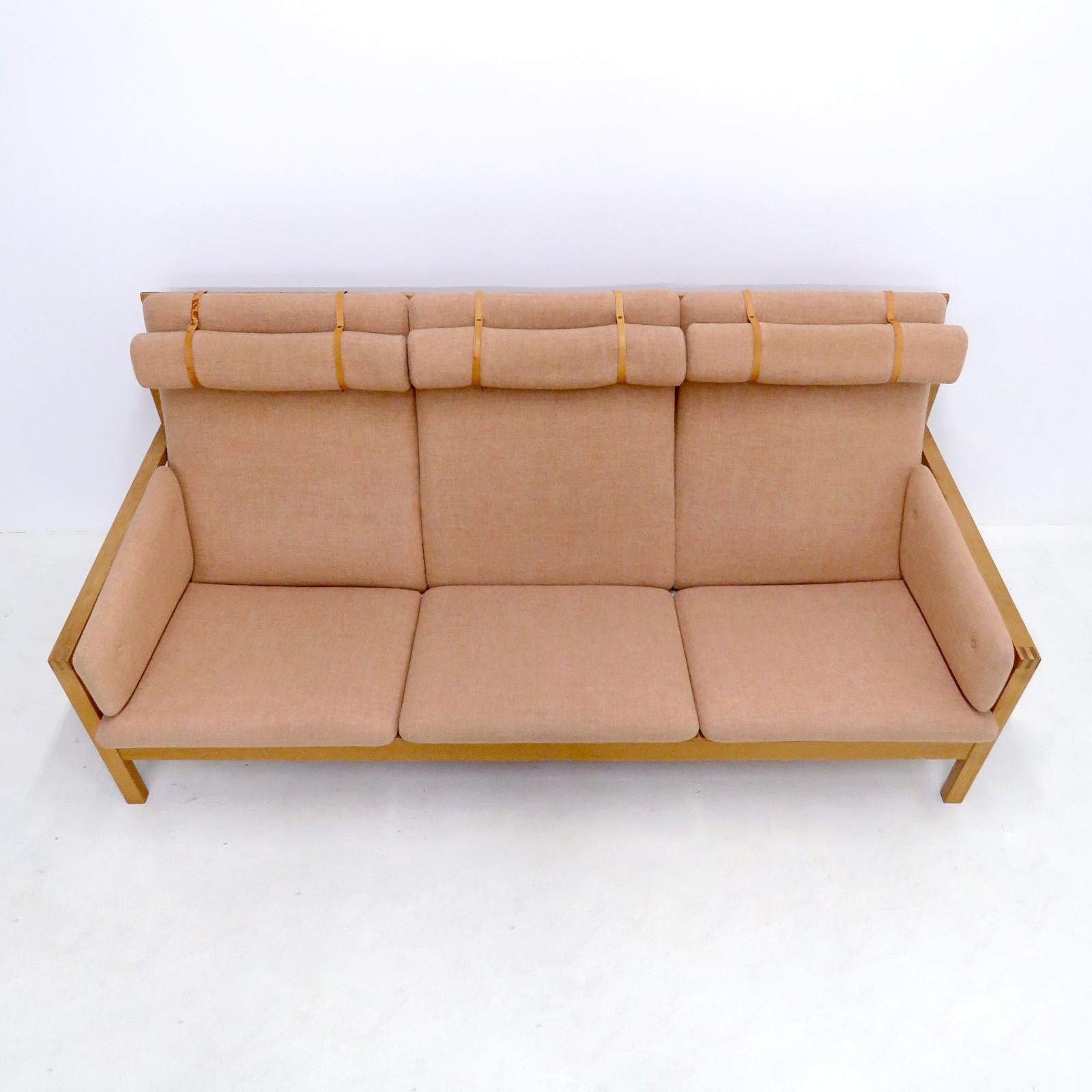Wunderschönes Dreisitzer-Sofa Modell Nr. 2253, entworfen von Børge Mogensen im Jahr 1963 und hergestellt von Frederica Stolefabrik, Dänemark, in original lachsfarbener Wolle mit Lederriemen auf einem Eichenholzrahmen, markiert.
Provenienz:
