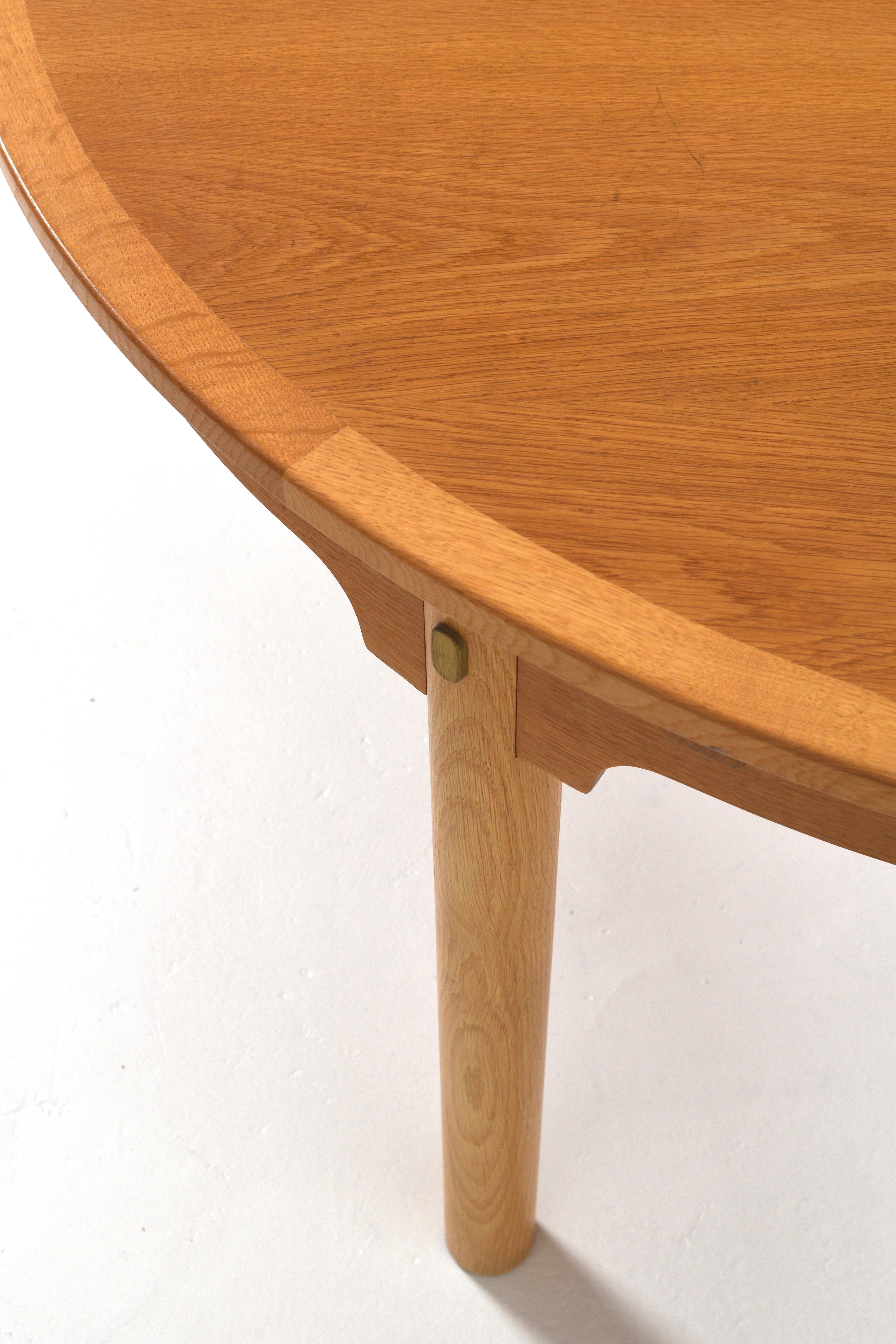 Cette table de salle à manger extensible de Børge Mogensen illustre l'essence du modernisme danois fonctionnel. Fabriquée en chêne avec d'élégantes ferrures en laiton, cette table allie des lignes épurées à une sophistication pratique. Sa forme
