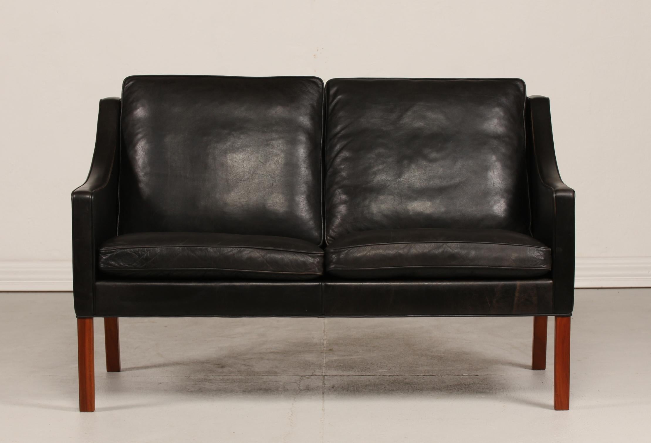 Danish vintage Børge Mogensen (1914-1972) sofa for 2 persons model no. 2208.
It's upholstered with the original black leather. The legs are made of mahogany. 
The cushions are filled inside with granules and natural feathers which gives the sofa a