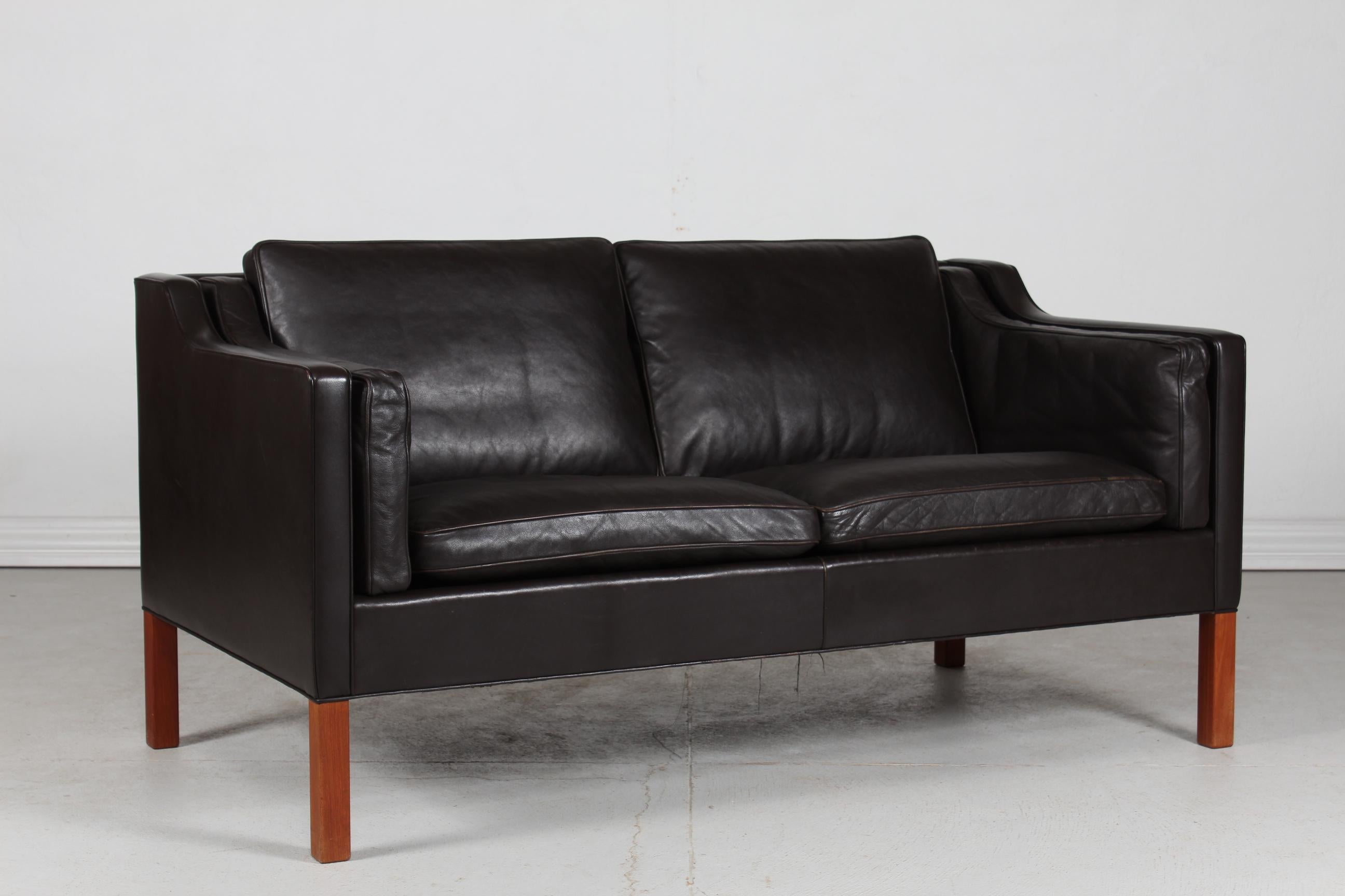 Danish vintage Børge Mogensen sofa 2 persons model 2212.
It's upholstered with the original dark mocha colored leather, almost black. 
The legs are made of solid teak with oil treatment.
The cushions are filled inside with granules and natural